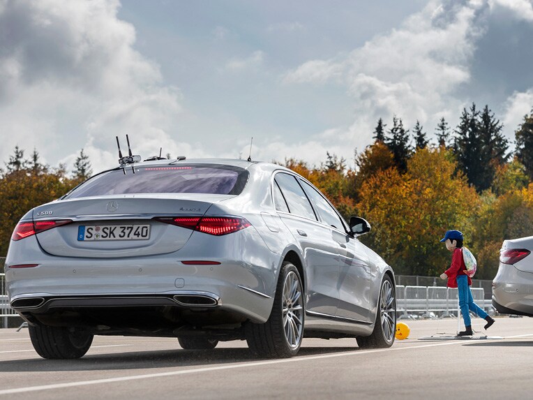 Kinder-Crashtest-Dummy vor bremsendem Mercedes.