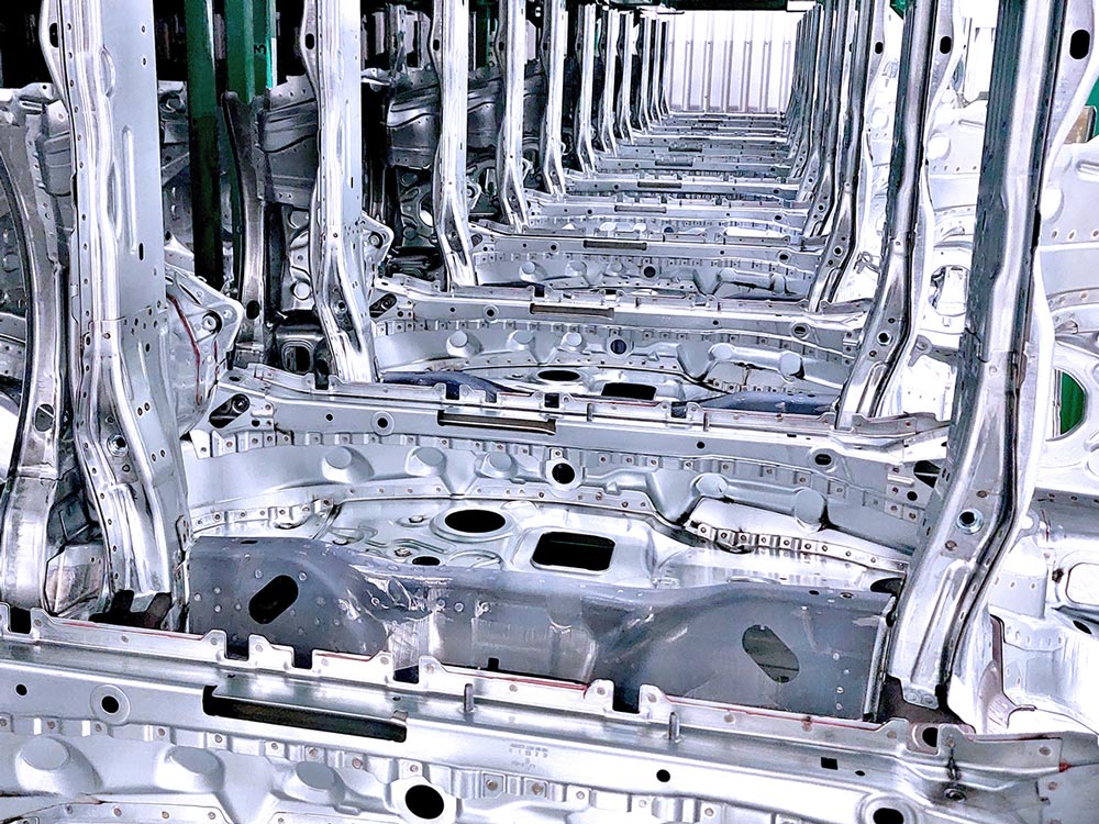 Karosserierohbauten Mehrere silberne Karosserierohbauten von Autos stehen in einer Reihe in einer Produktionshalle