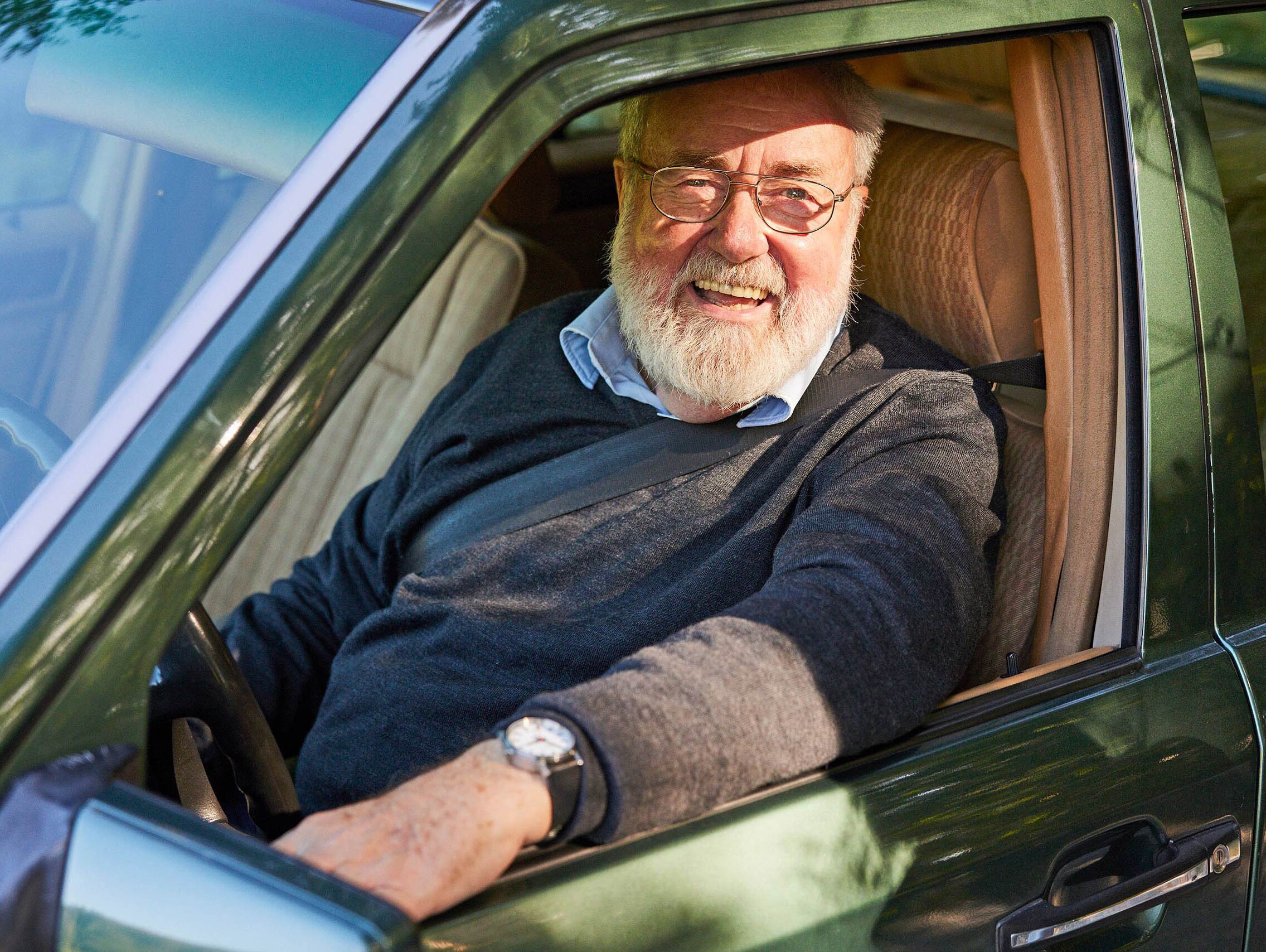 Un homme d’un certain âge est assis dans une vieille voiture verte