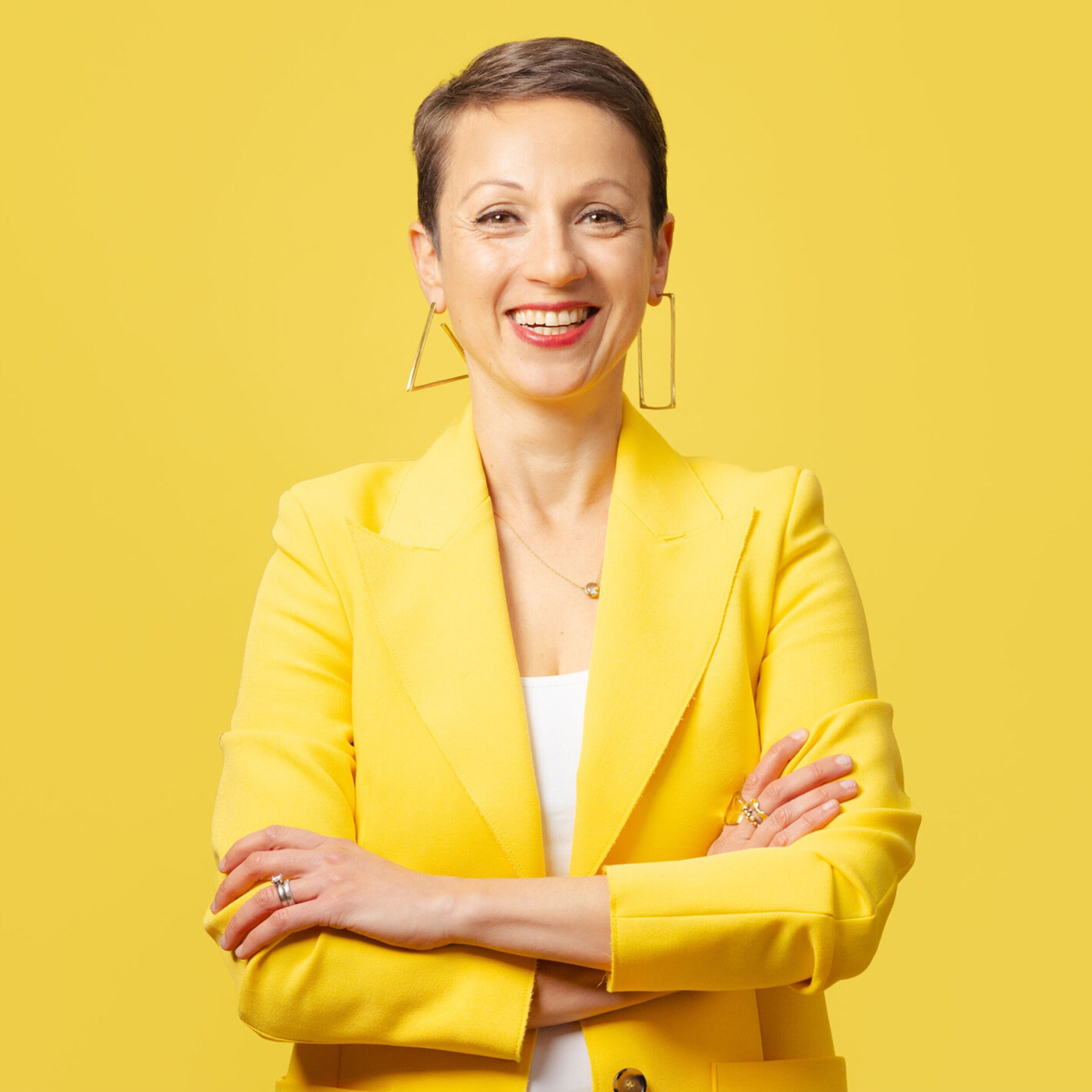 Eine lächelnde Frau namens Nataly Kogan in einem gelben Blazer.