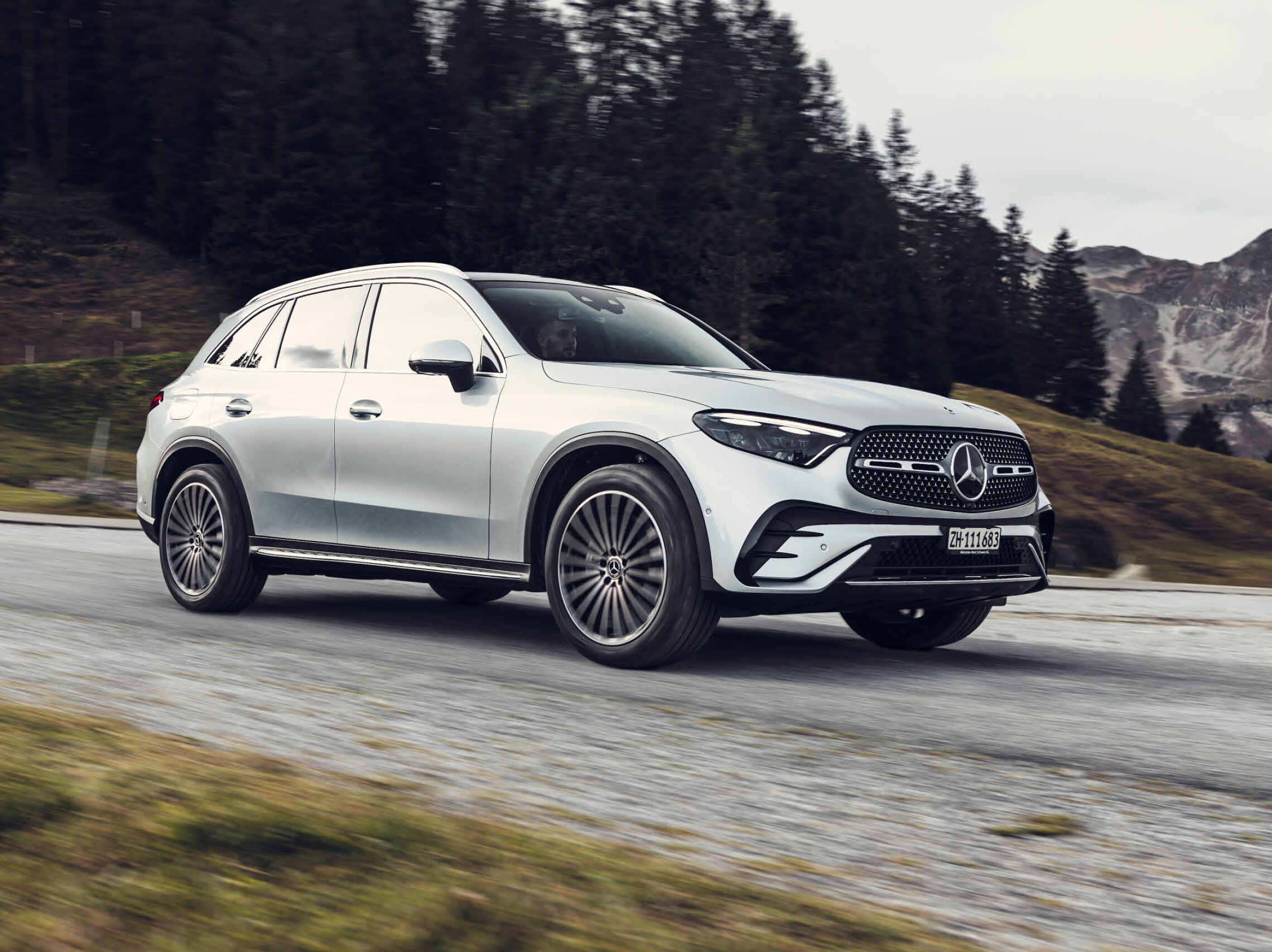 Weisser Mercedes SUV fährt durch eine Berglandschaft.