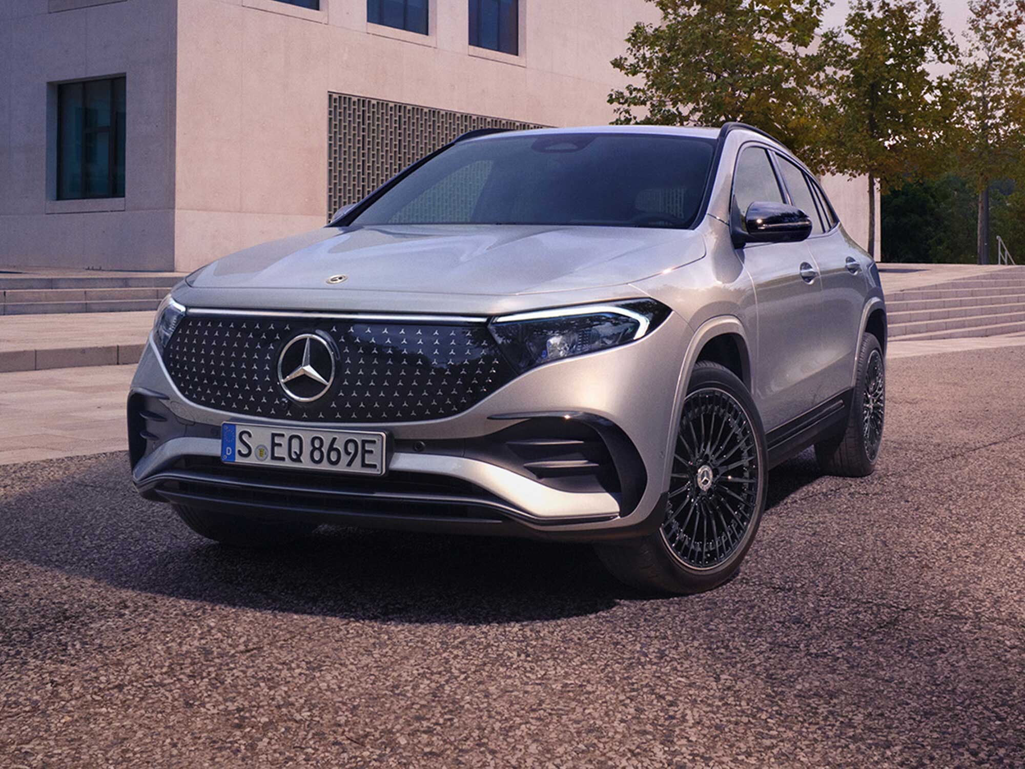 Ein Mercedes-Benz EQA steht vor einem modernen Gebäude seitlich geparkt. 