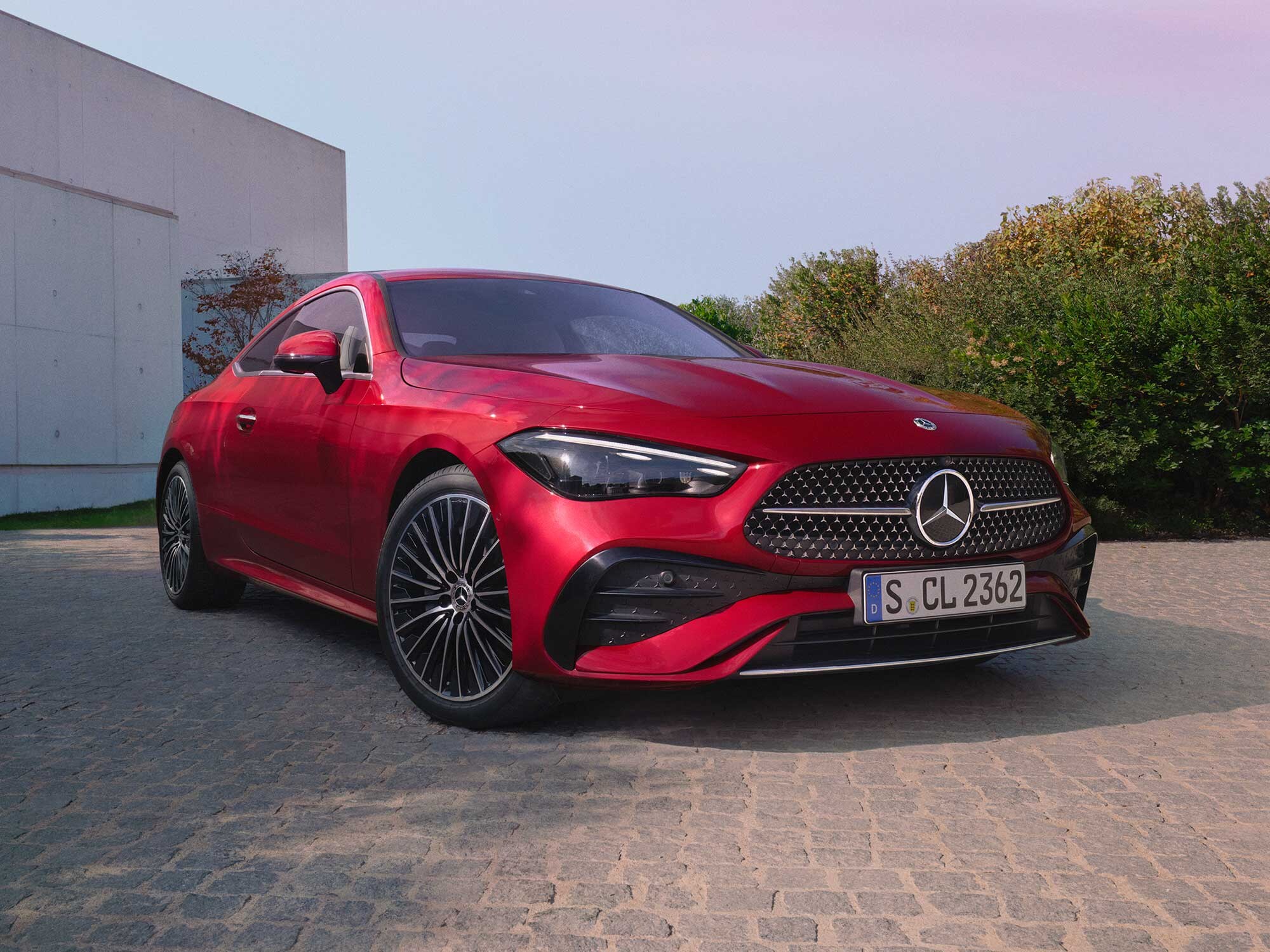 Mercedes-Benz CLE Coupé seitlich geparkt auf einer Auffahrt, vor einem modernen Gebäude.