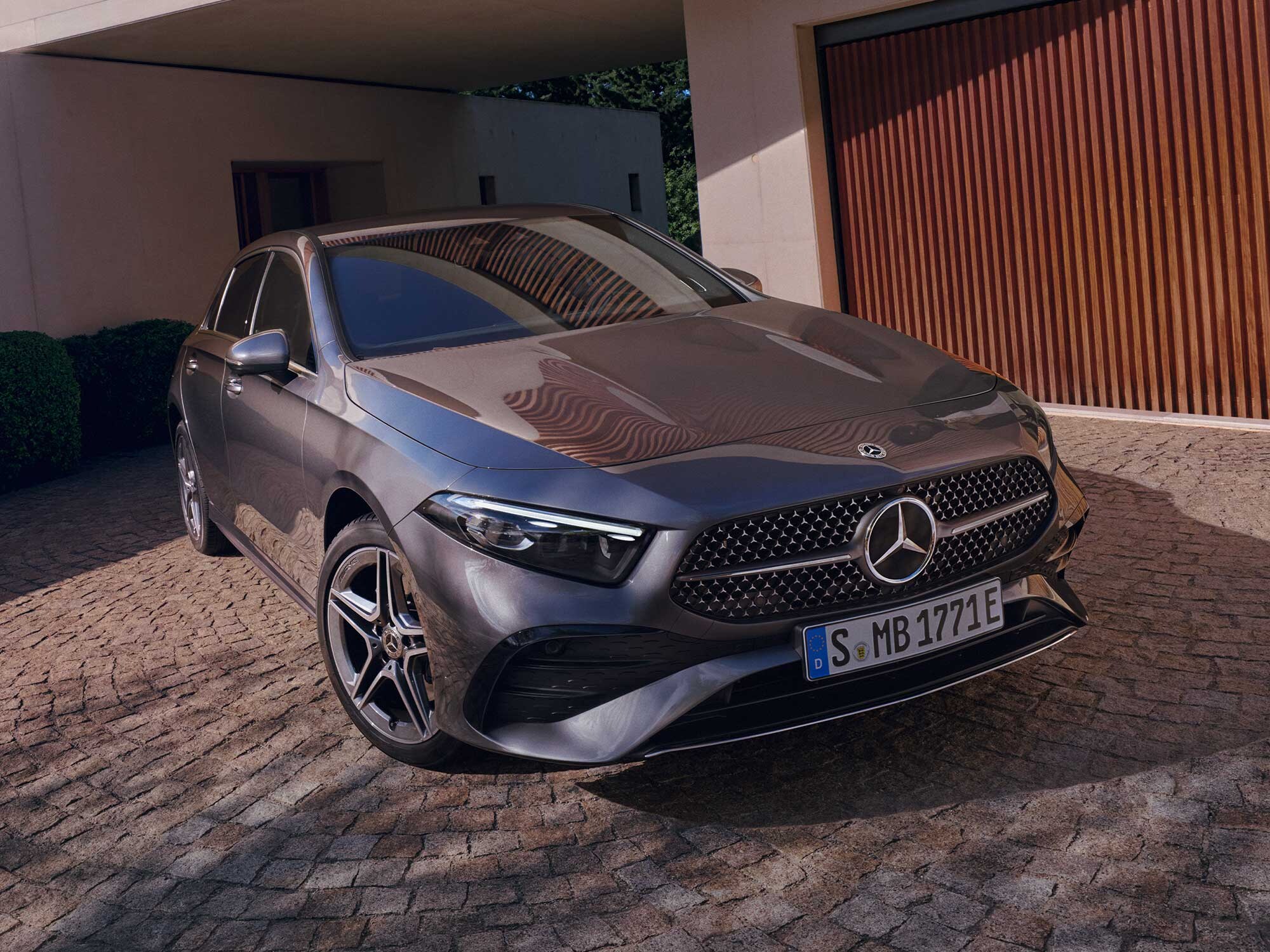 Mercedes-Benz A-Klasse, schräg von vorn vor moderner Garage mit Holzverkleidung.