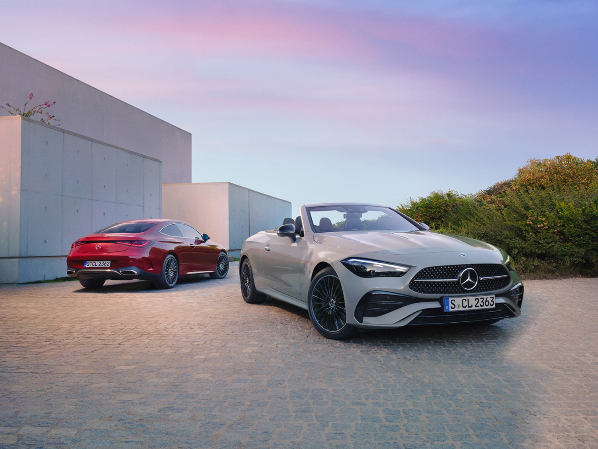 Zwei Mercedes-Benz AMG Line Fahrzeuge vor einem modernen Gebäude.