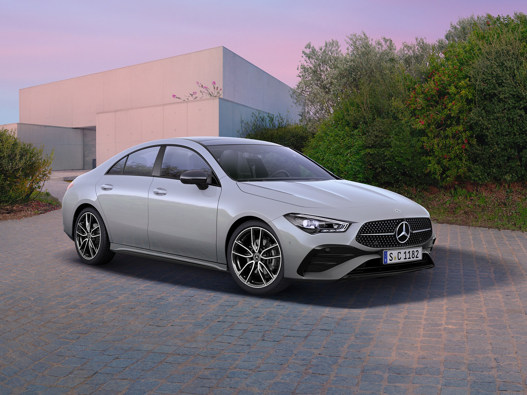 Mercedes-Benz CLA Coupé seitlich geparkt vor einem modernen Gebäude mit Einfahrt.