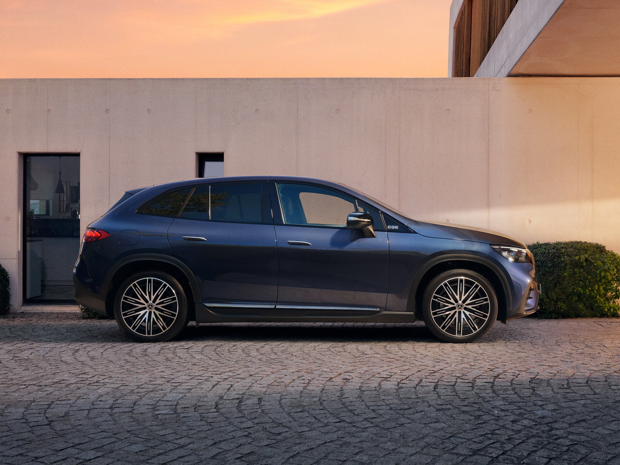 Mercedes-Benz EQE SUV parcheggiata lateralmente davanti a una casa moderna.
