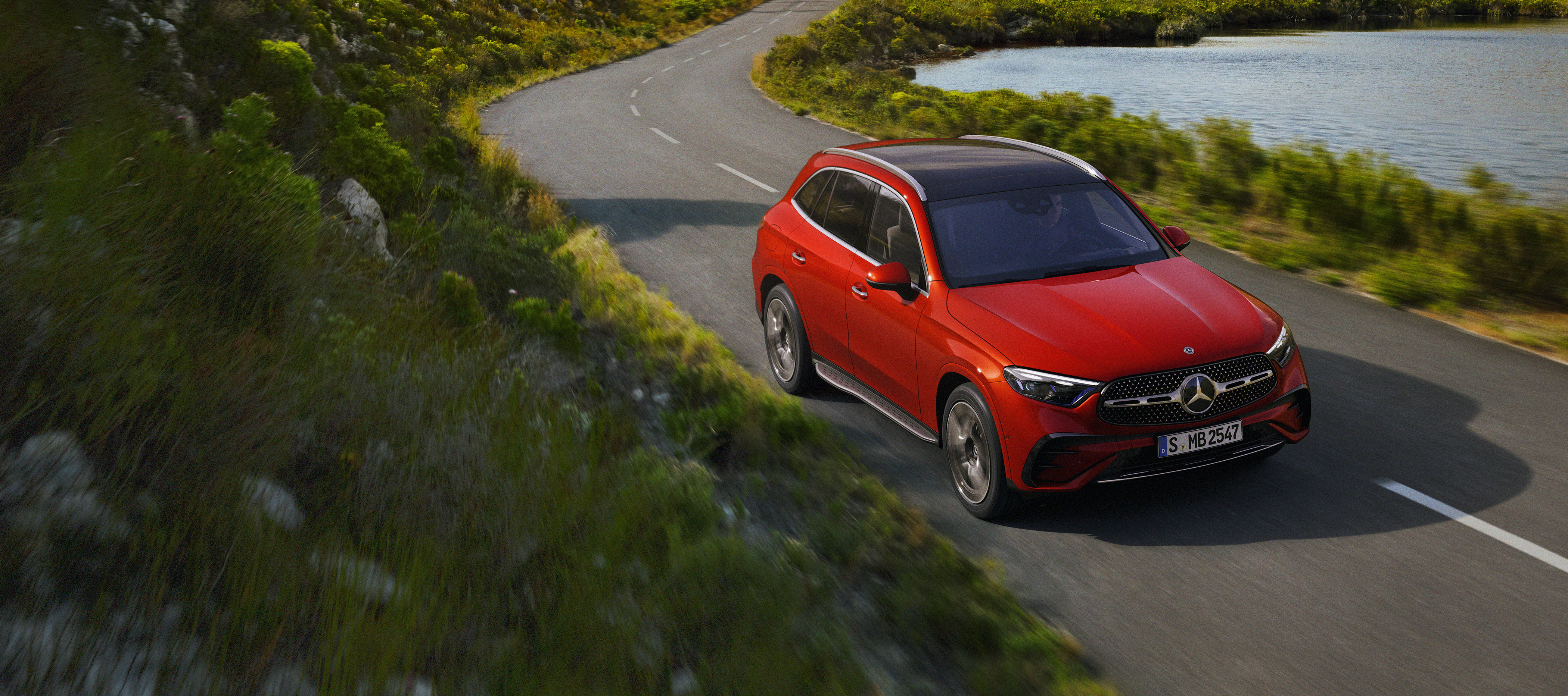 Mercedes-Benz GLC rouge Une Mercedes-Benz GLC rouge sur une route de campagne sinueuse.