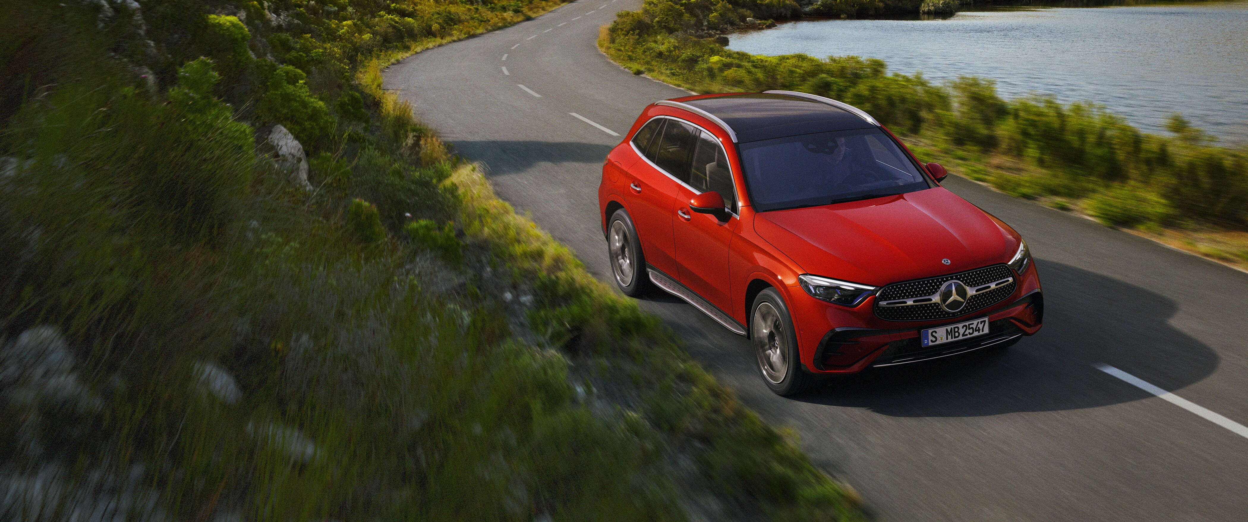 Une Mercedes-Benz GLC rouge sur une route de campagne sinueuse.
