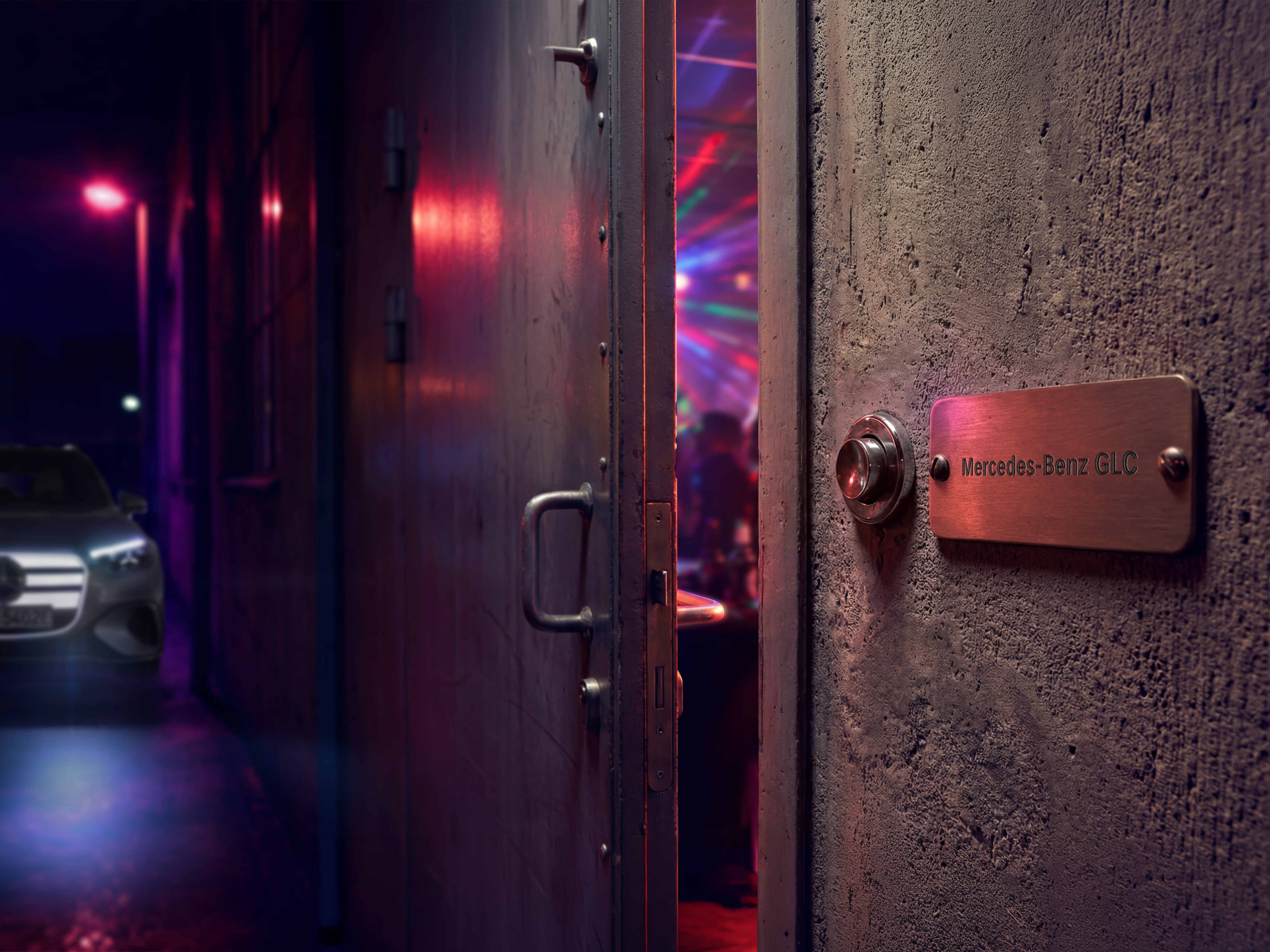 Una porta socchiusa con una targhetta Mercedes-Benz GLC lascia intravedere un loft party dall’atmosfera suggestiva, illuminata da luci colorate.