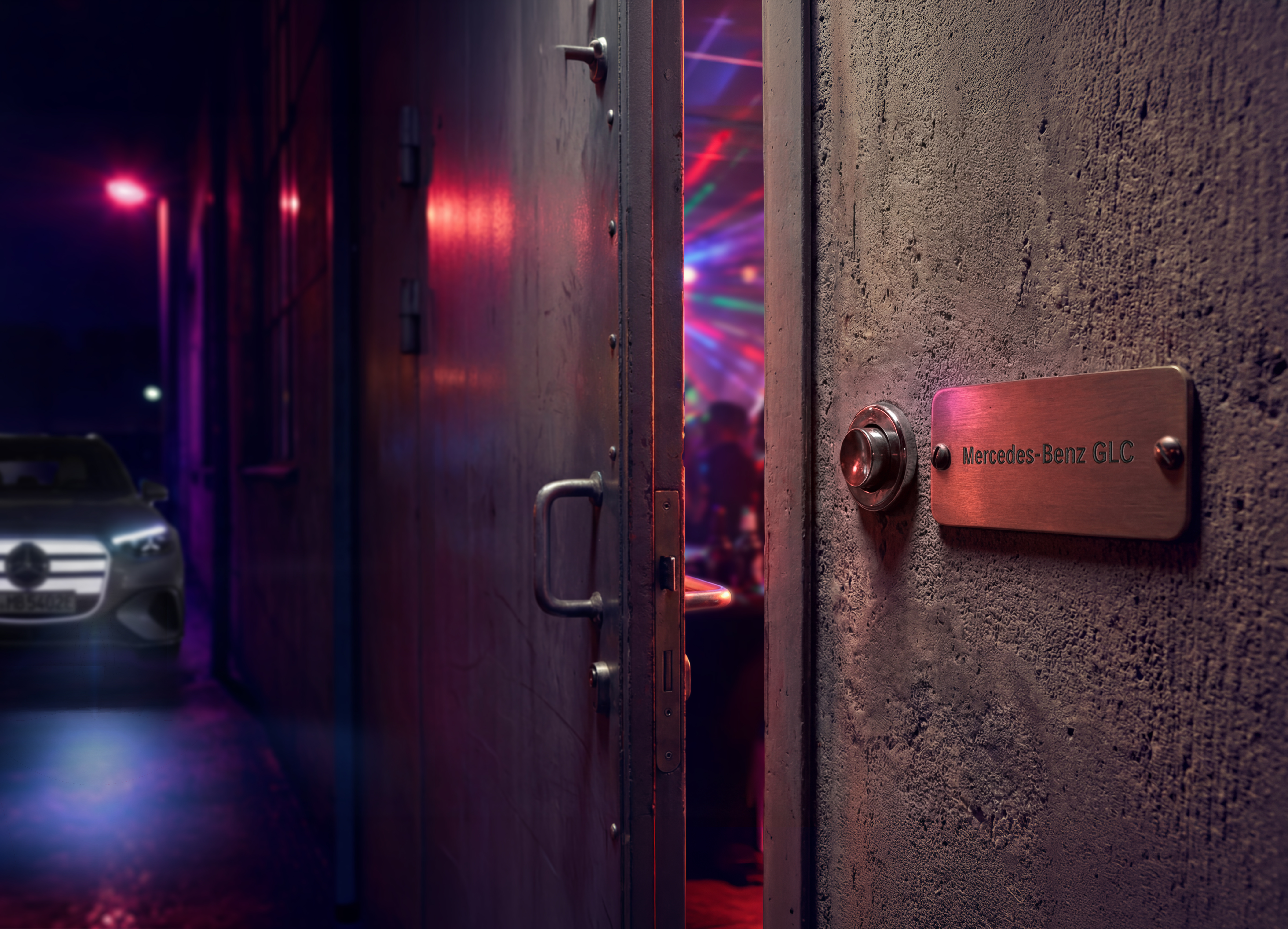 Benvenuti al loft party Una porta socchiusa con una targhetta Mercedes-Benz GLC lascia intravedere un loft party dall’atmosfera suggestiva, illuminata da luci colorate.