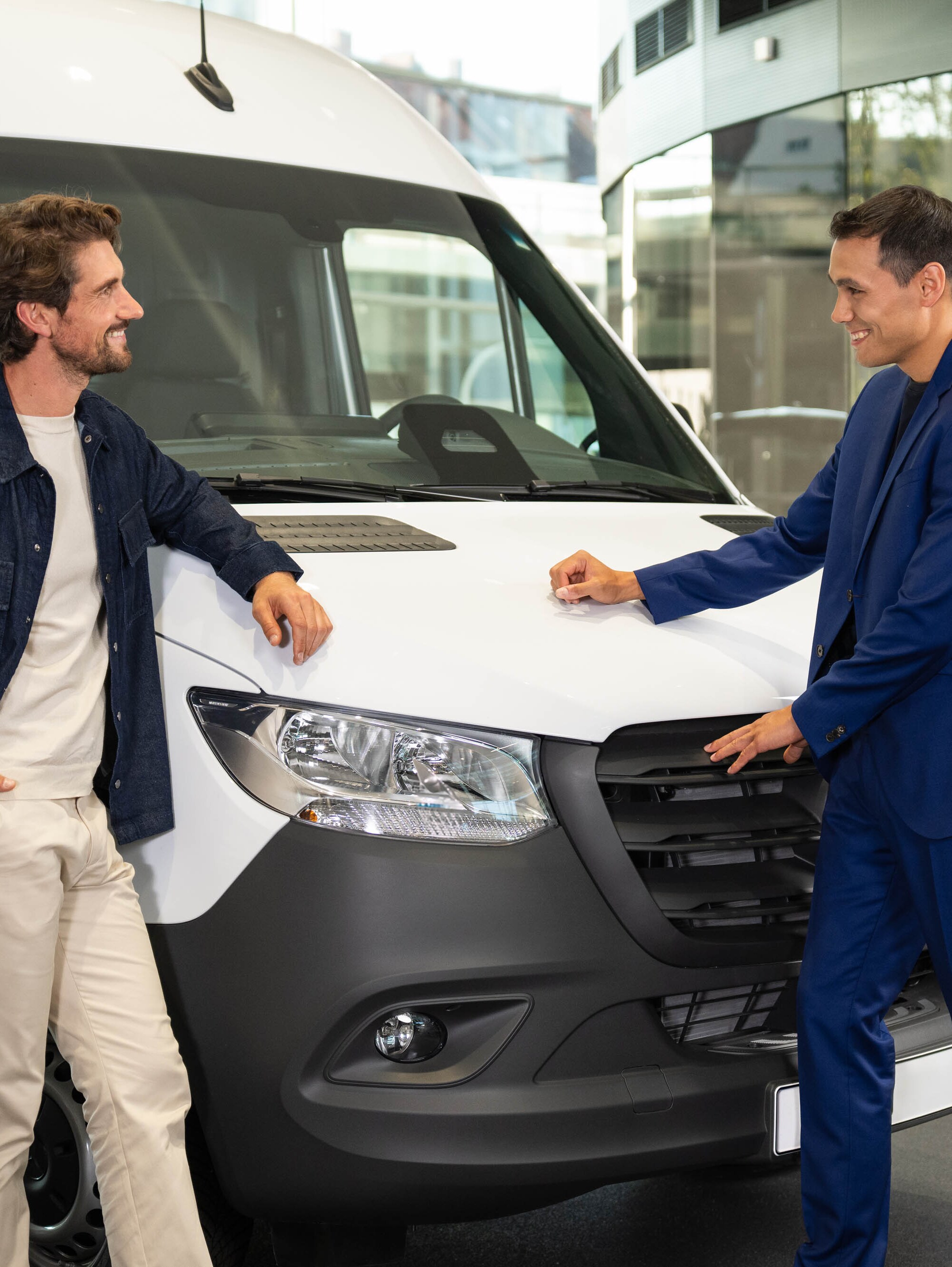 Zwei Personen lehnen sich an einen Mercedes-Benz Van und unterhalten sich.