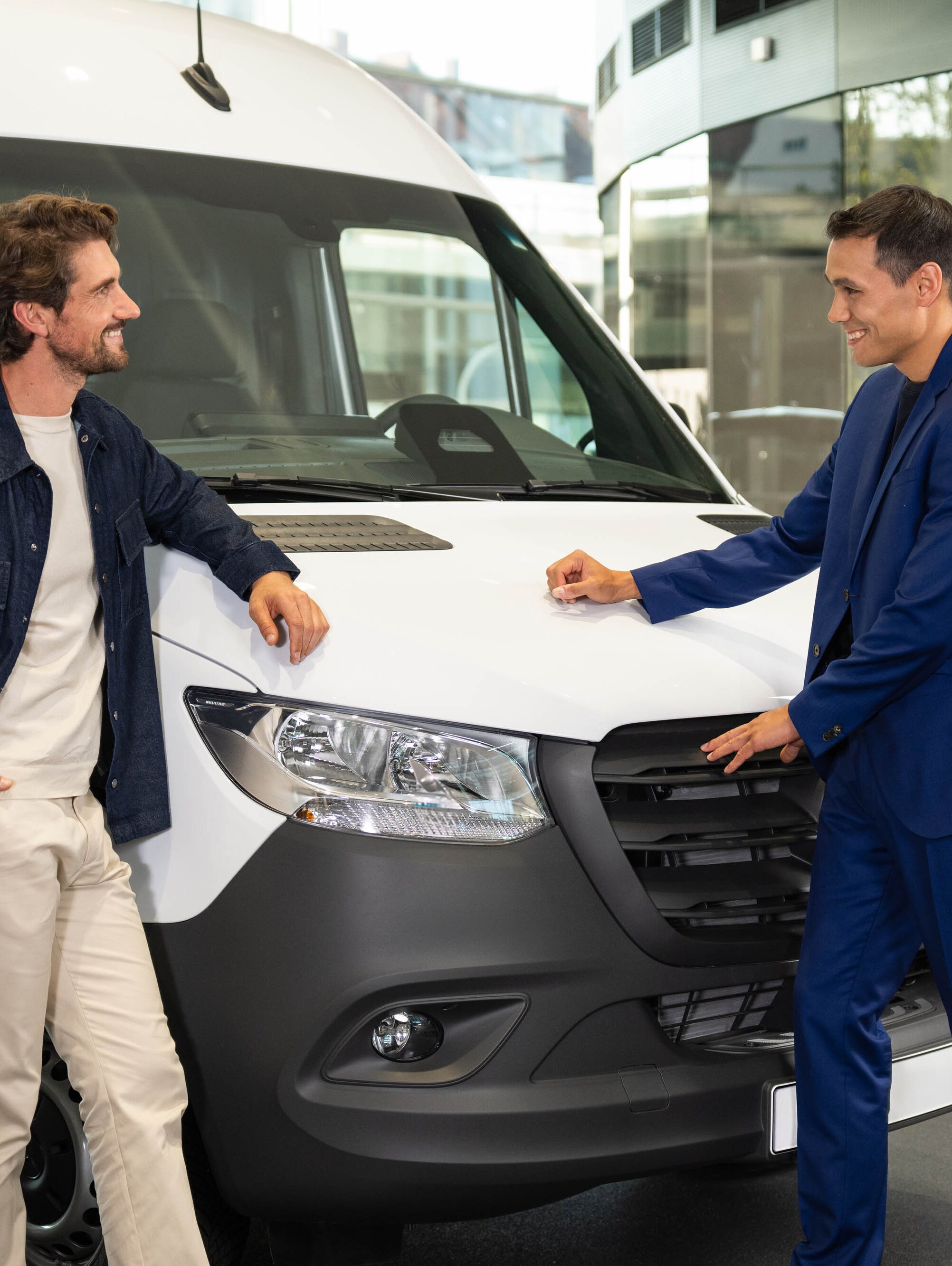 Deux personnes appuyées contre un van Mercedes-Benz et ayant une conversation.