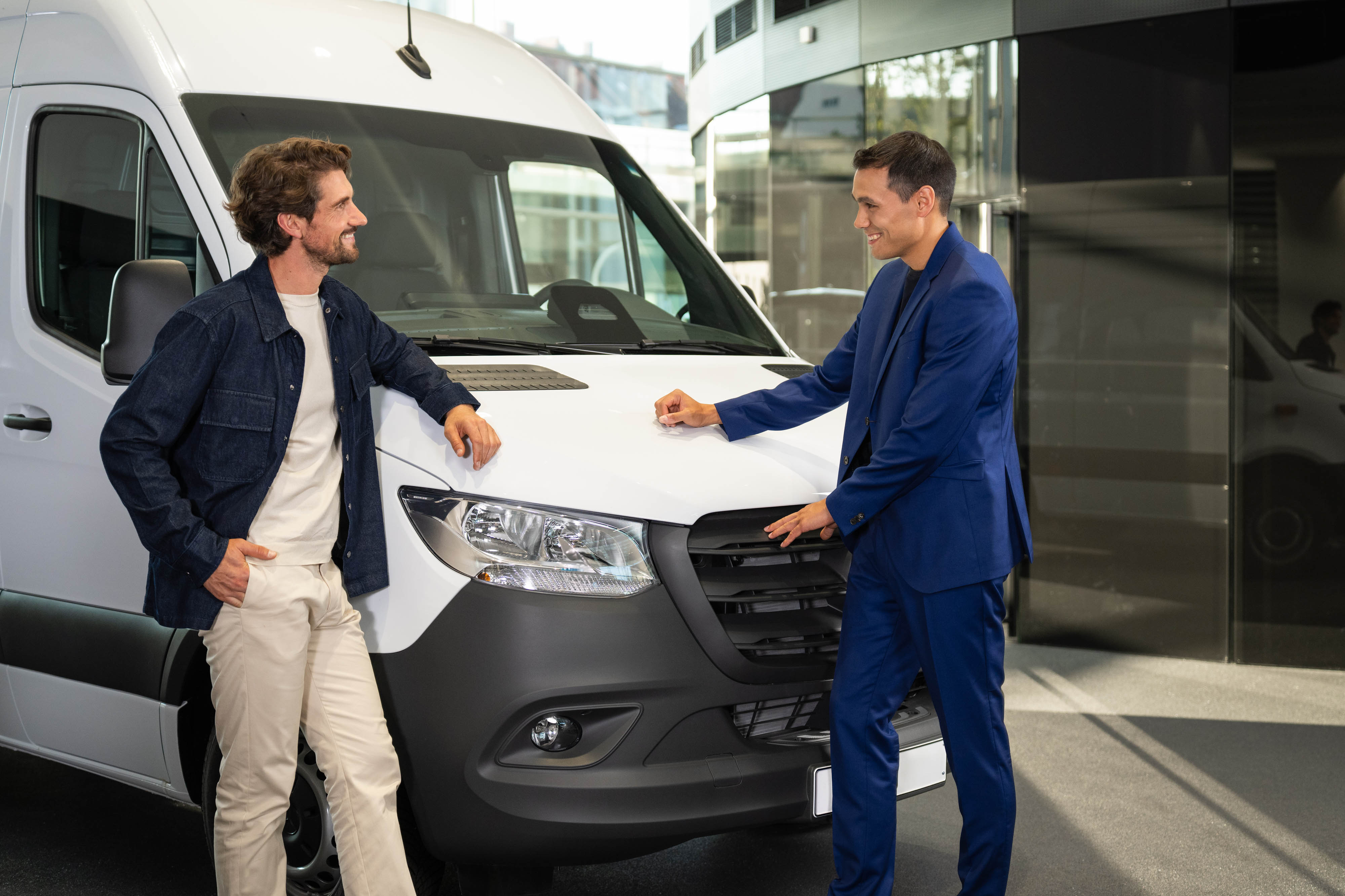 Offres de leasing pour véhicules d’occasion Mercedes-Benz Deux personnes appuyées contre un van Mercedes-Benz et ayant une conversation.