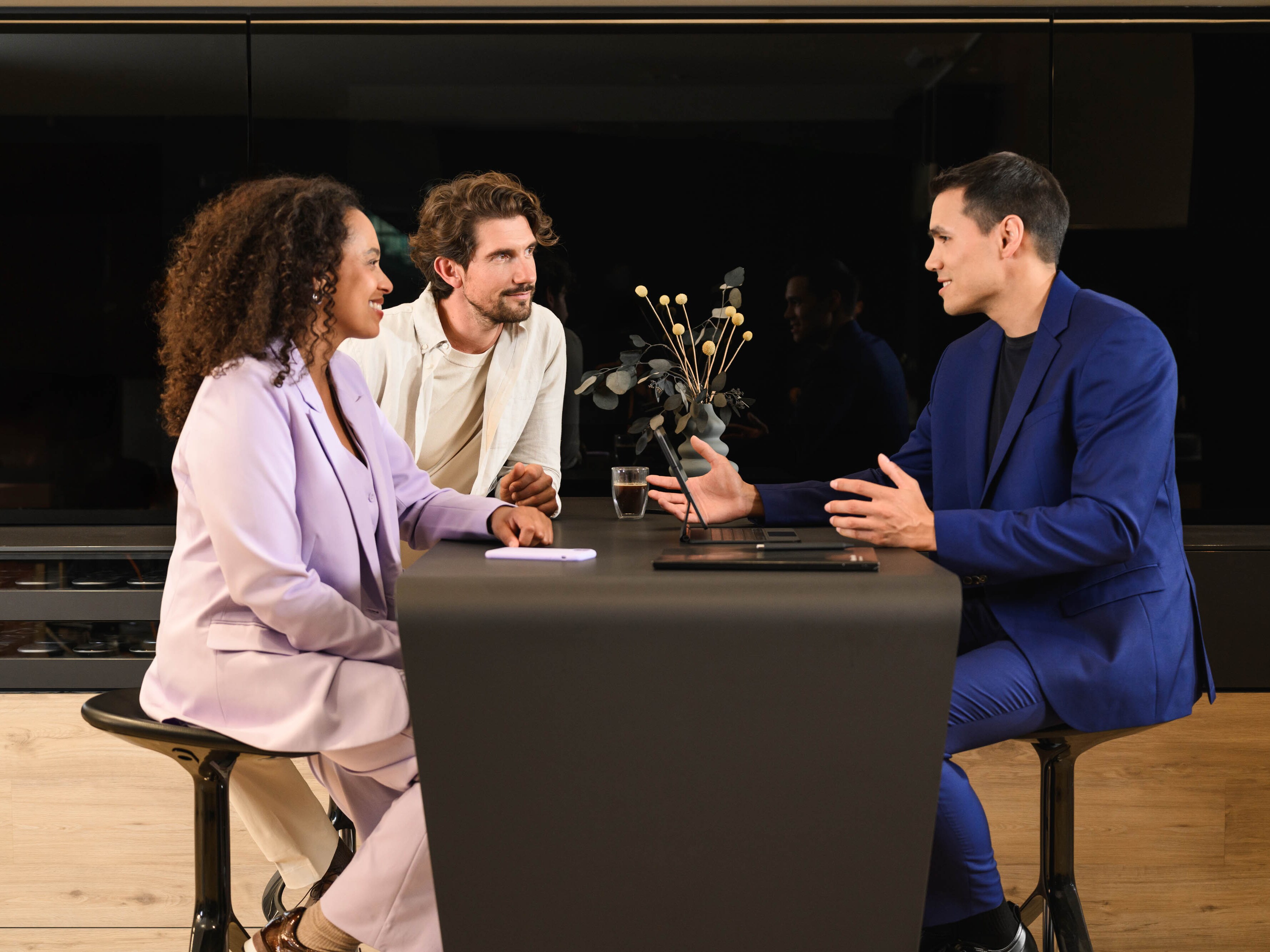 Trois personnes sont assises à une table et discutent.