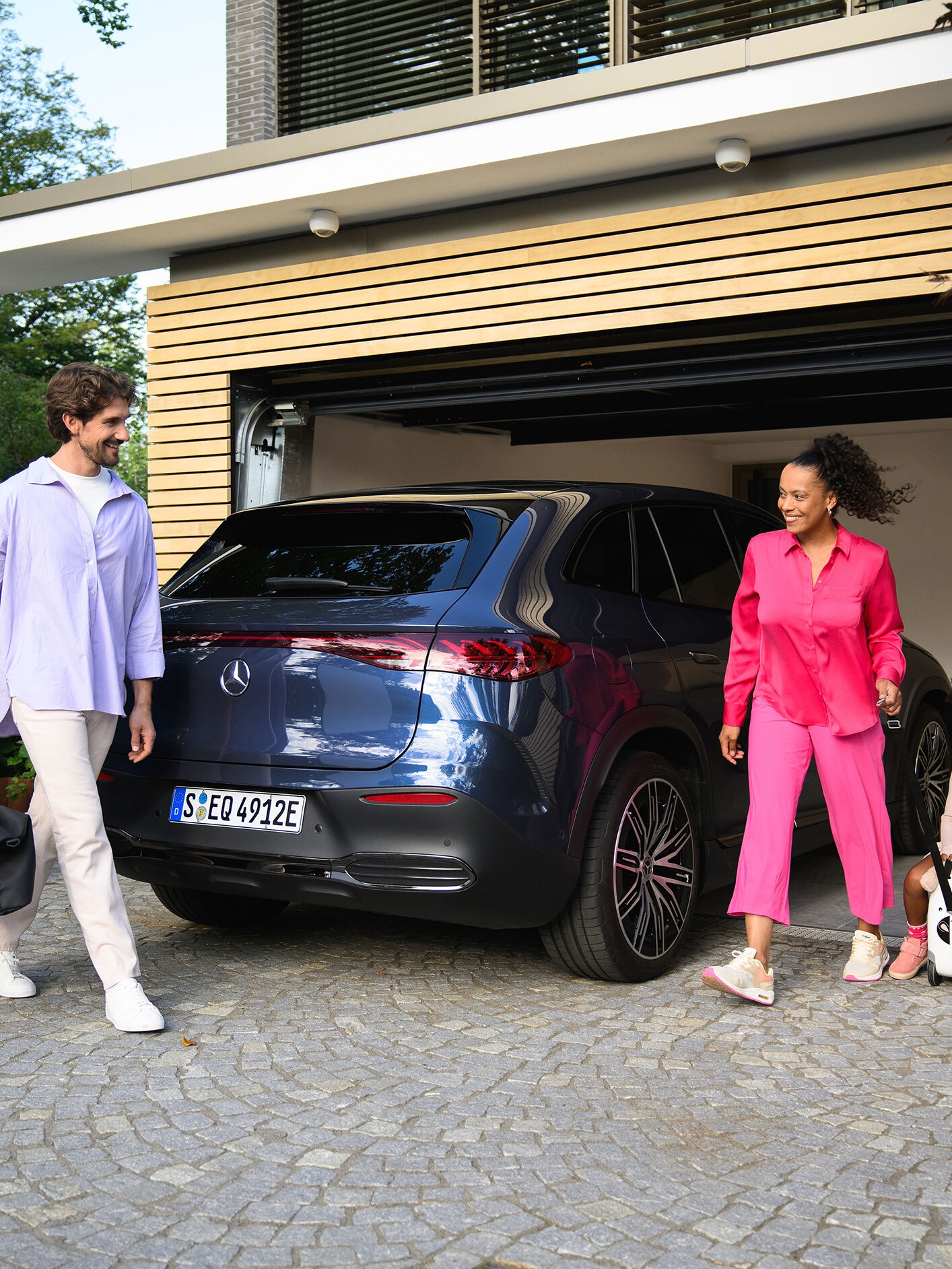 Zwei Personen und ein Kind, die zu ihrem Mercedes-Benz gehen.