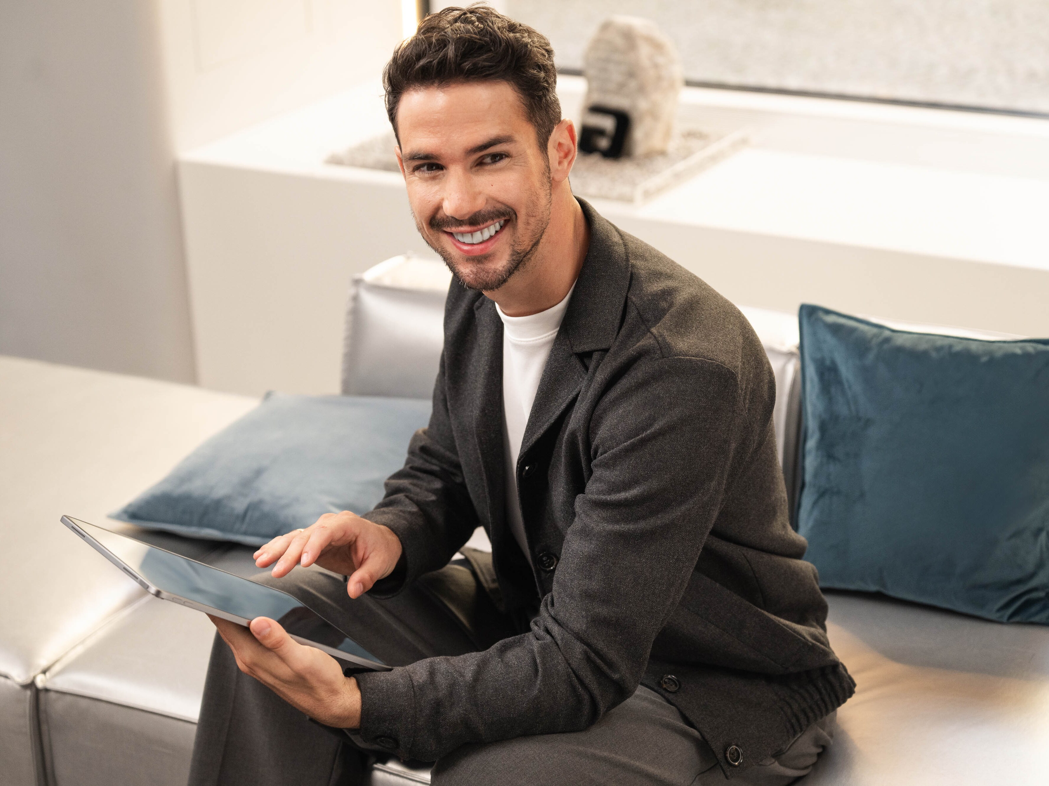 Una persona seduta su un divano sta utilizzando il suo dispositivo mobile.