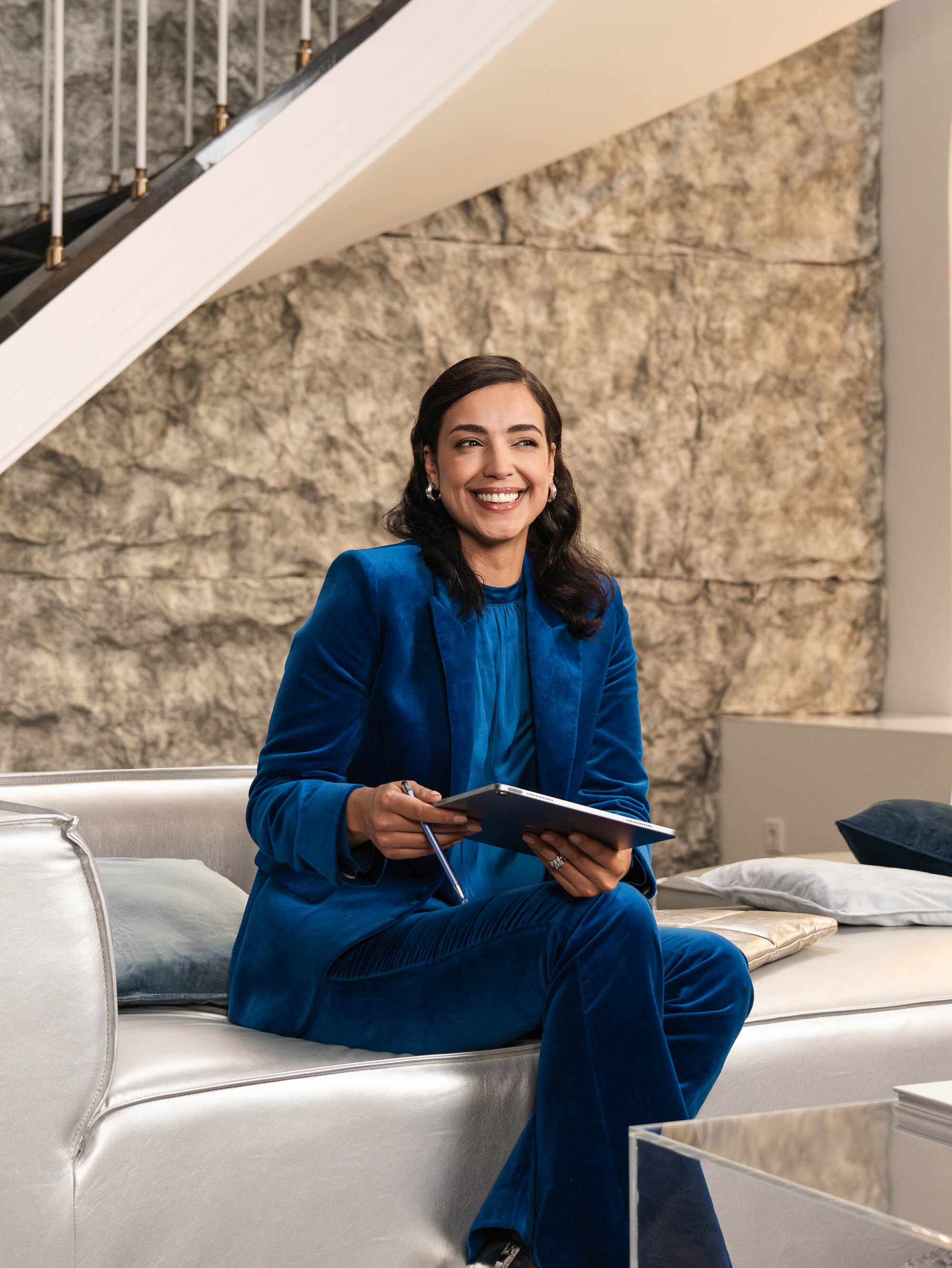 Eine Person sitzt auf einem Sofa und hält ein mobiles Gerät in der Hand.