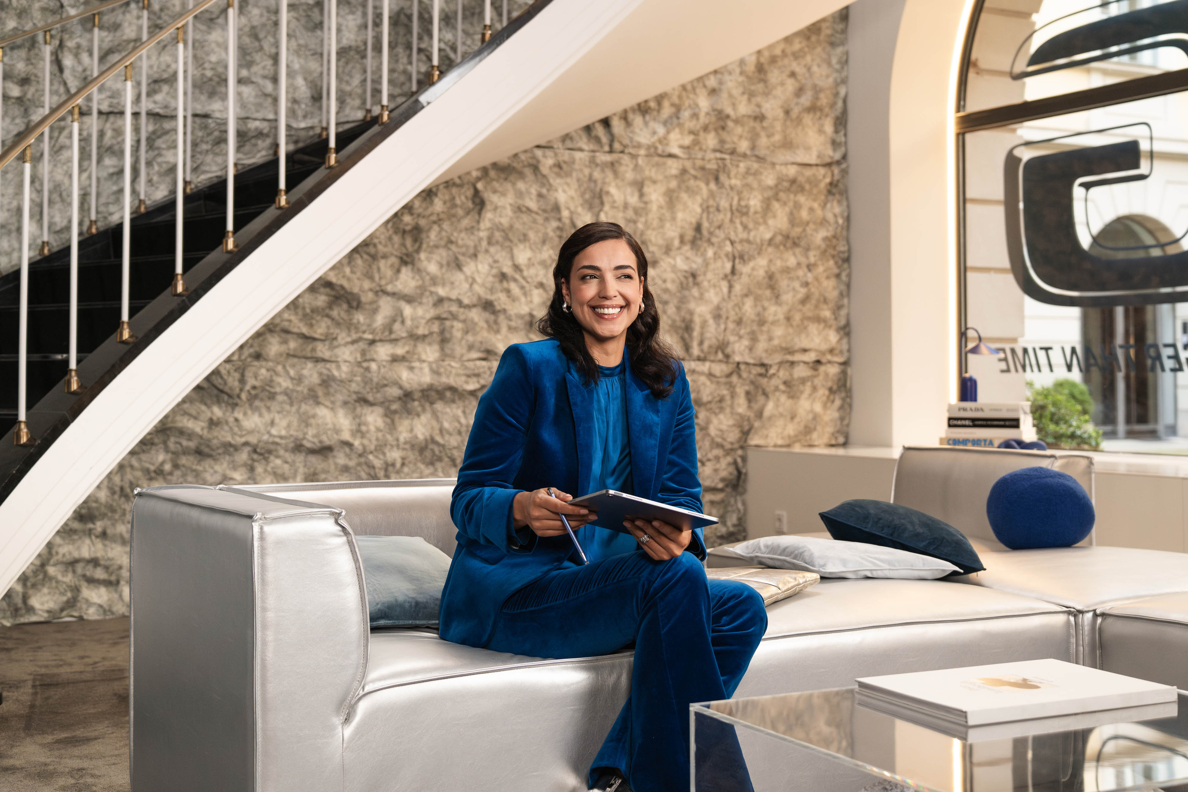 Vantaggi di Mercedes-Benz Rent Una persona è seduta su un divano e tiene un dispositivo mobile in mano.