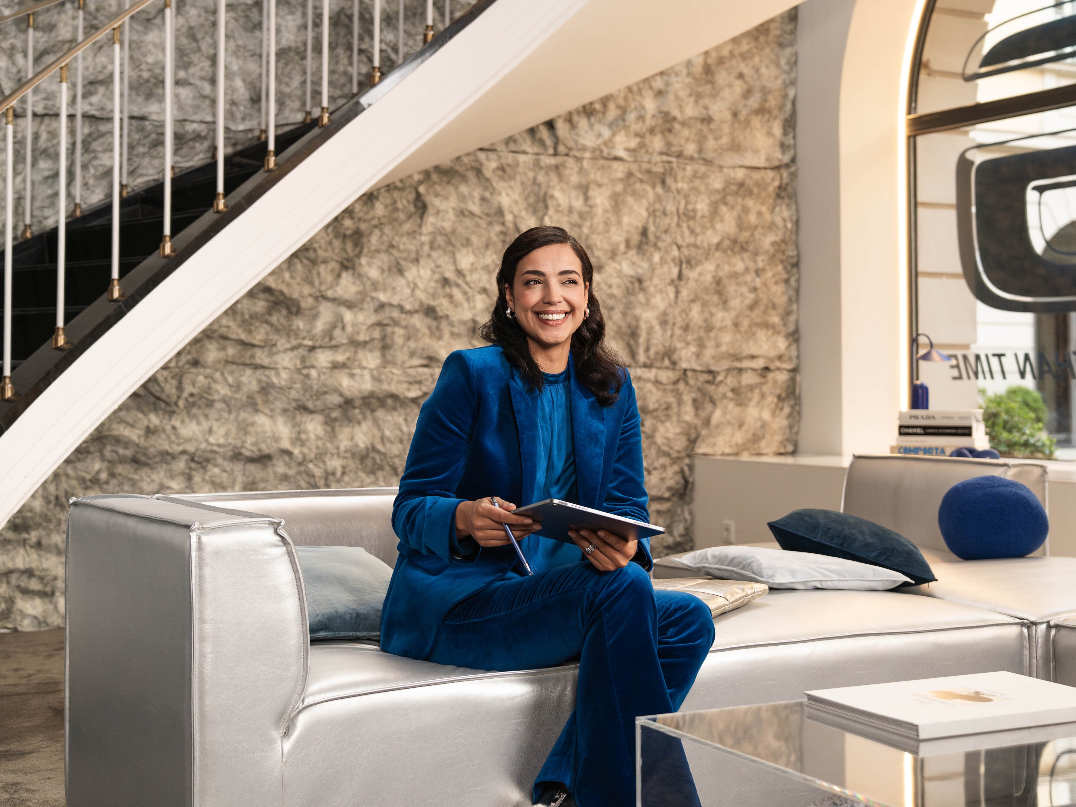 Une personne est assise sur un canapé et tient un appareil mobile à la main.