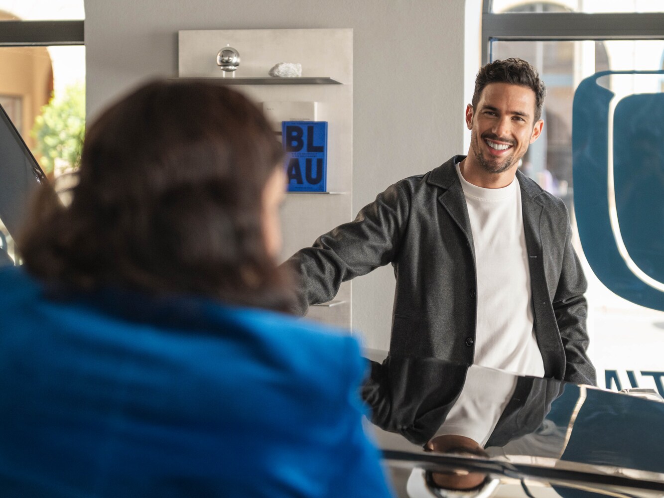 Due persone si appoggiano al cofano di una Mercedes-Benz e conversano.