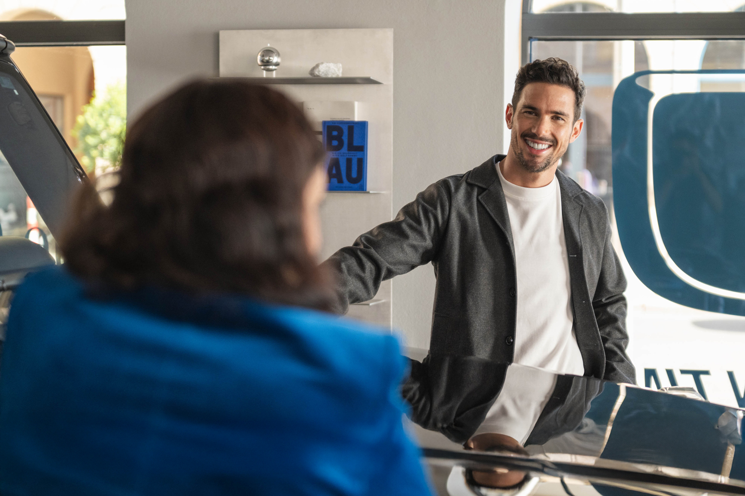 Mietlösungen von Mercedes-Benz Rent Zwei Personen lehnen sich an eine Motorhaube eines Mercedes-Benz und unterhalten sich.