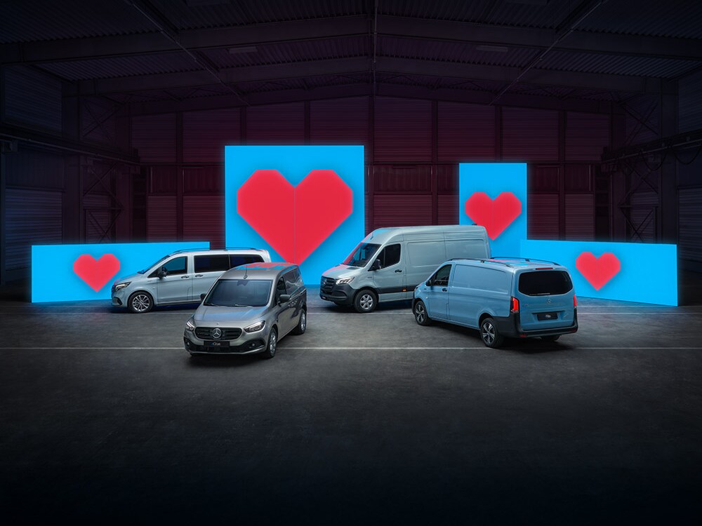Différents modèles de vans électriques sont placés devant des murs lumineux bleus, chacun avec un cœur rouge.