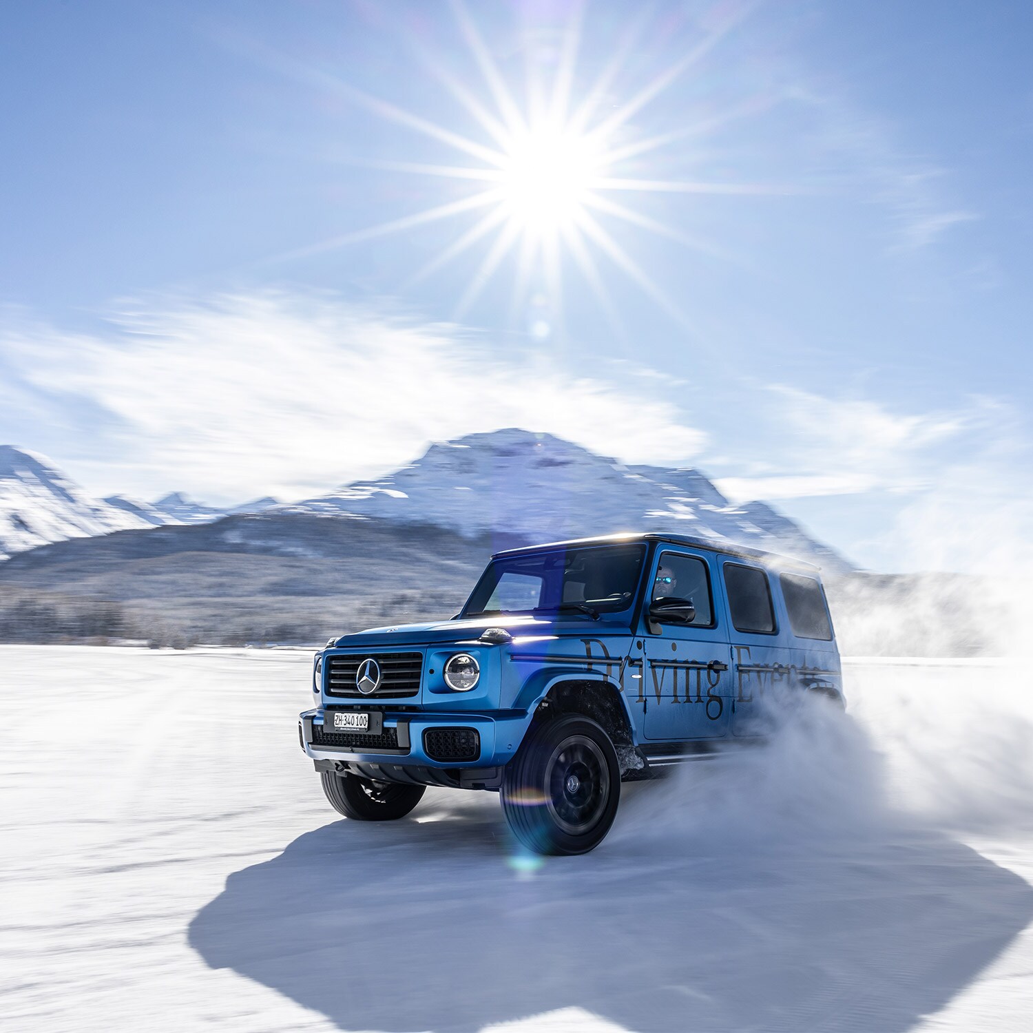Mercedes-Benz Classe G roulant sur une surface enneigée avec un paysage montagneux en arrière-plan.