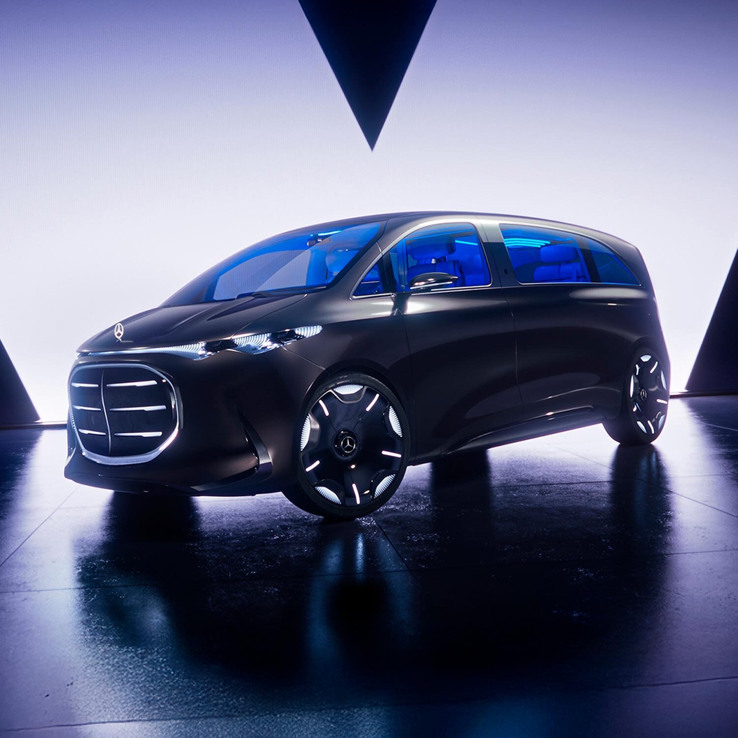 Vari modelli di van elettrici si trovano davanti a pareti illuminate di blu, ognuno con un cuore rosso.