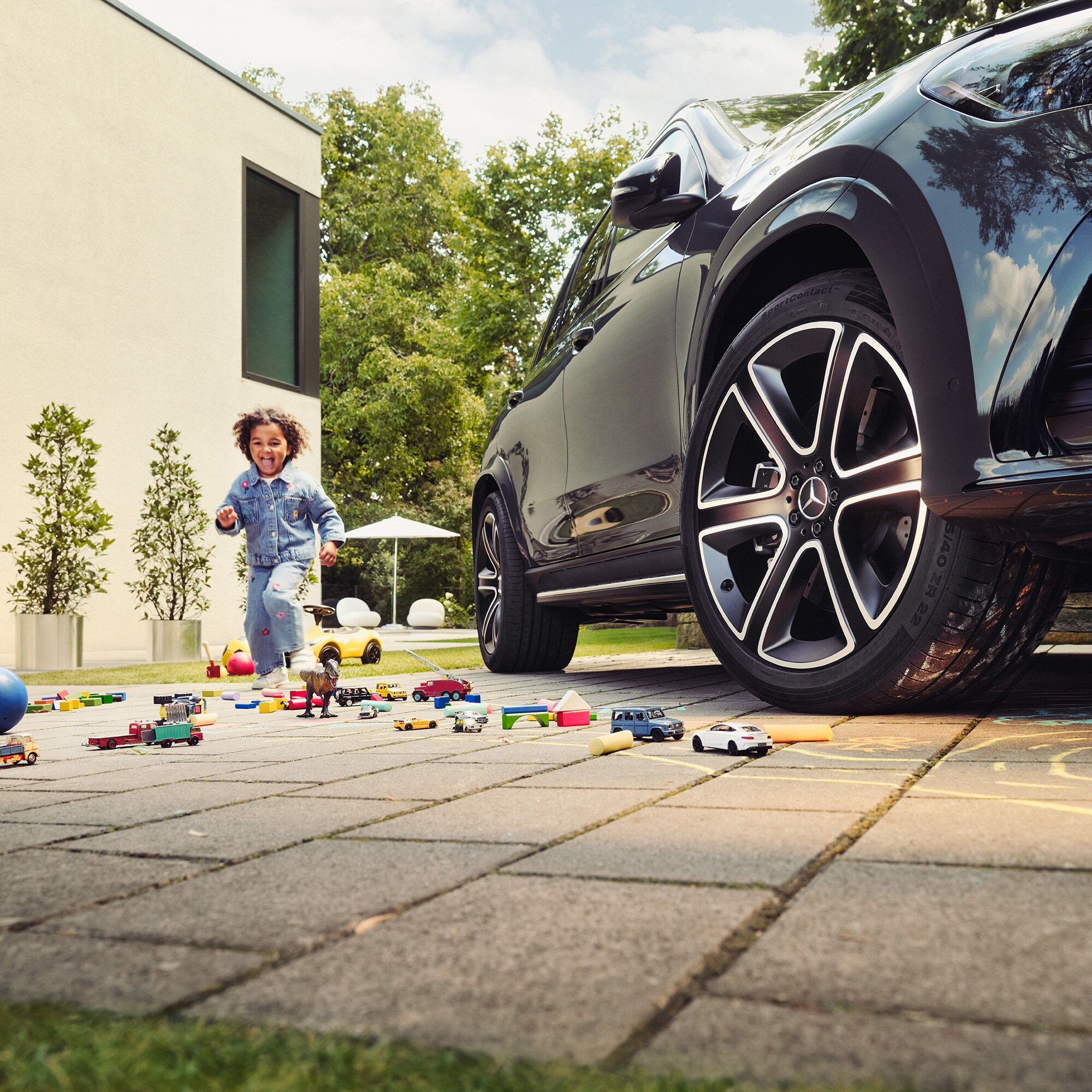 Ein Kind spielt mit Kreide neben einem Mercedes-Benz