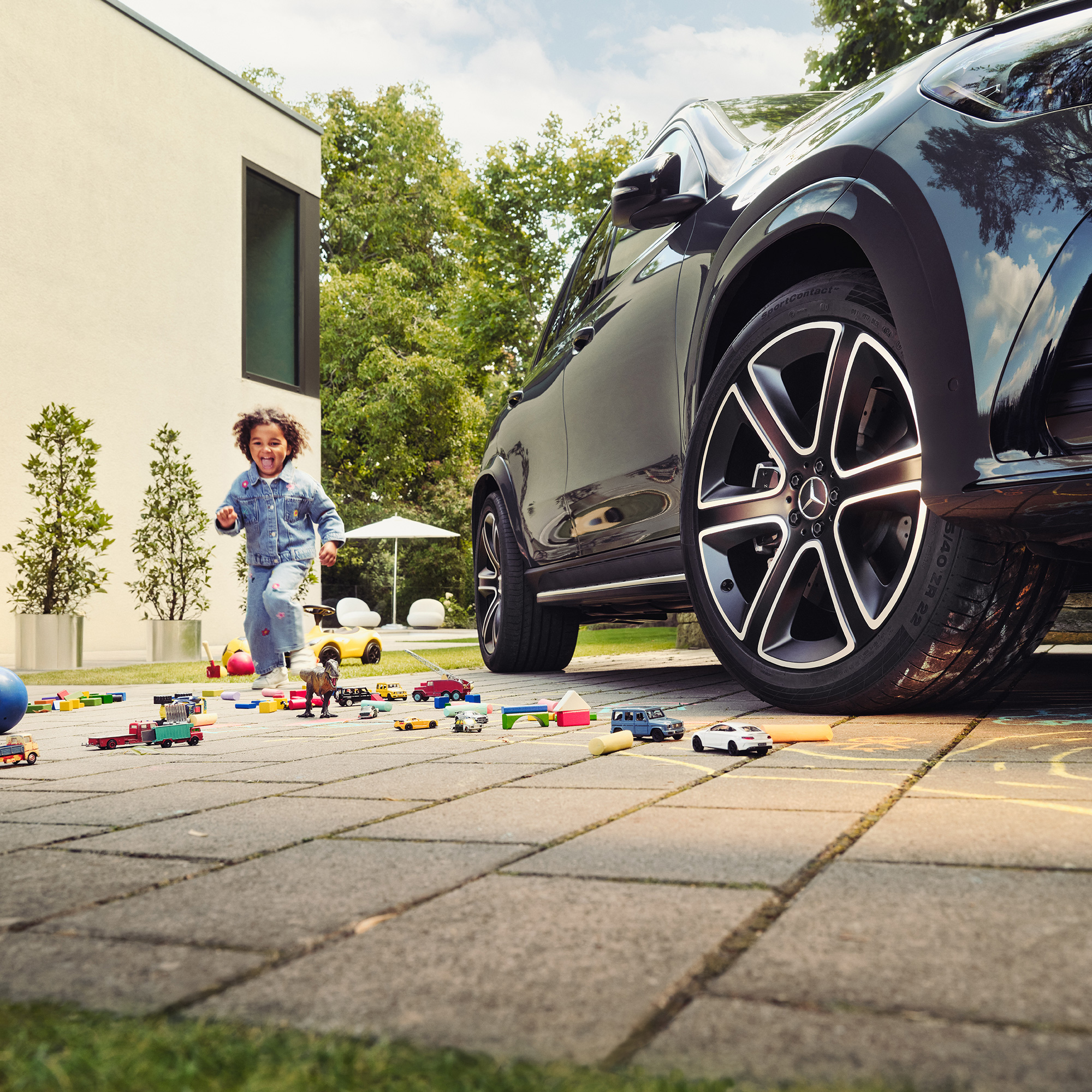 Ein Kind spielt mit Kreide neben einem Mercedes-Benz