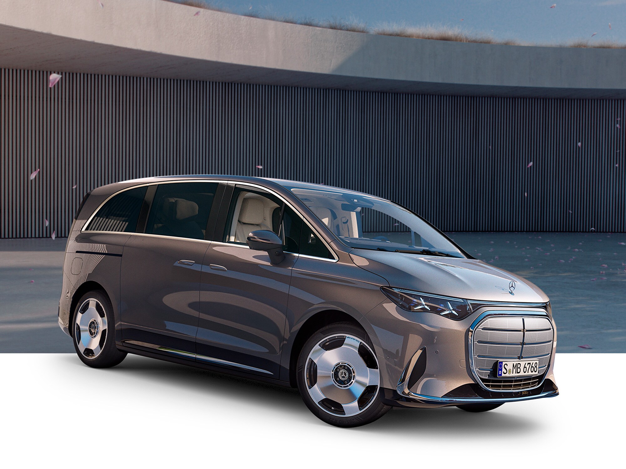 Gezeigt wird halb Freigestellter VLE von Mercedes-Benz. Parkend vor einem modernem Gebäude mit einem Kirschbaum an der Seite.