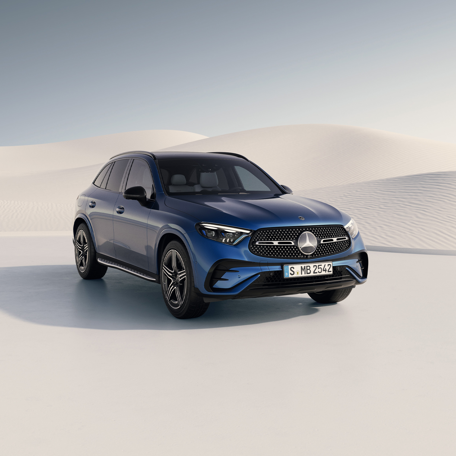 Nos modèles spéciaux SUV Mercedes bleu sur une route dans un paysage de dunes claires.