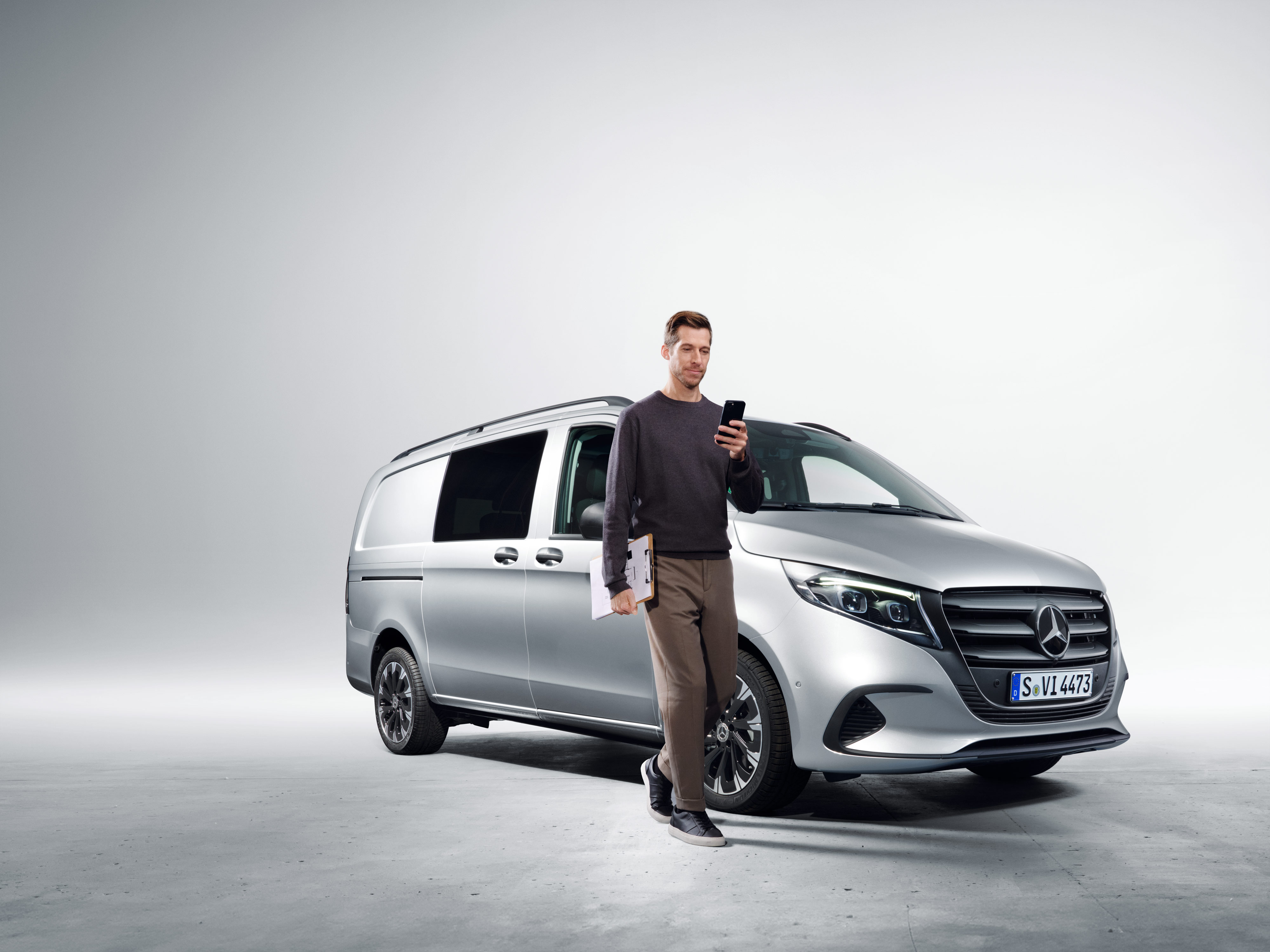 Mercedes-Benz Store | Digital Extra | Mercedes-Benz Une personne avec un smartphone devant une Mercedes-Benz.