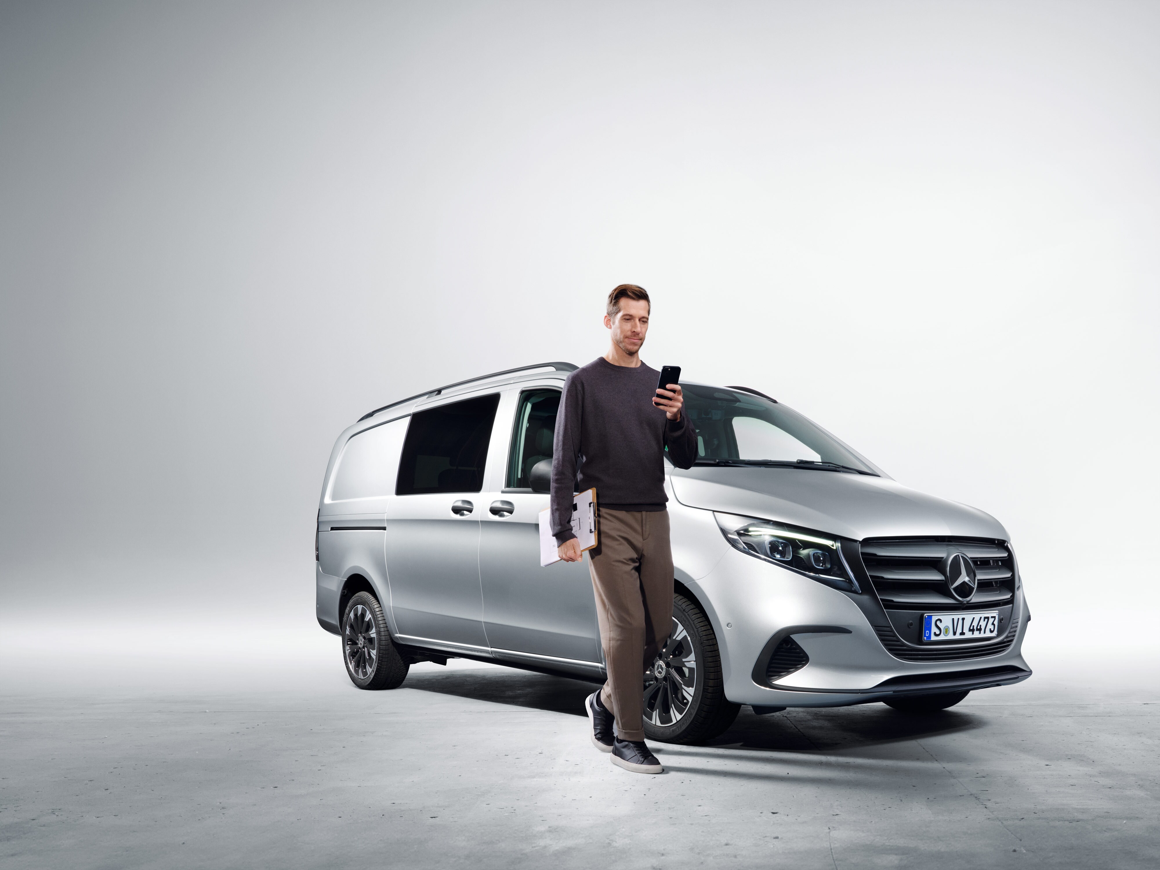 Una persona con uno smartphone davanti a una Mercedes-Benz