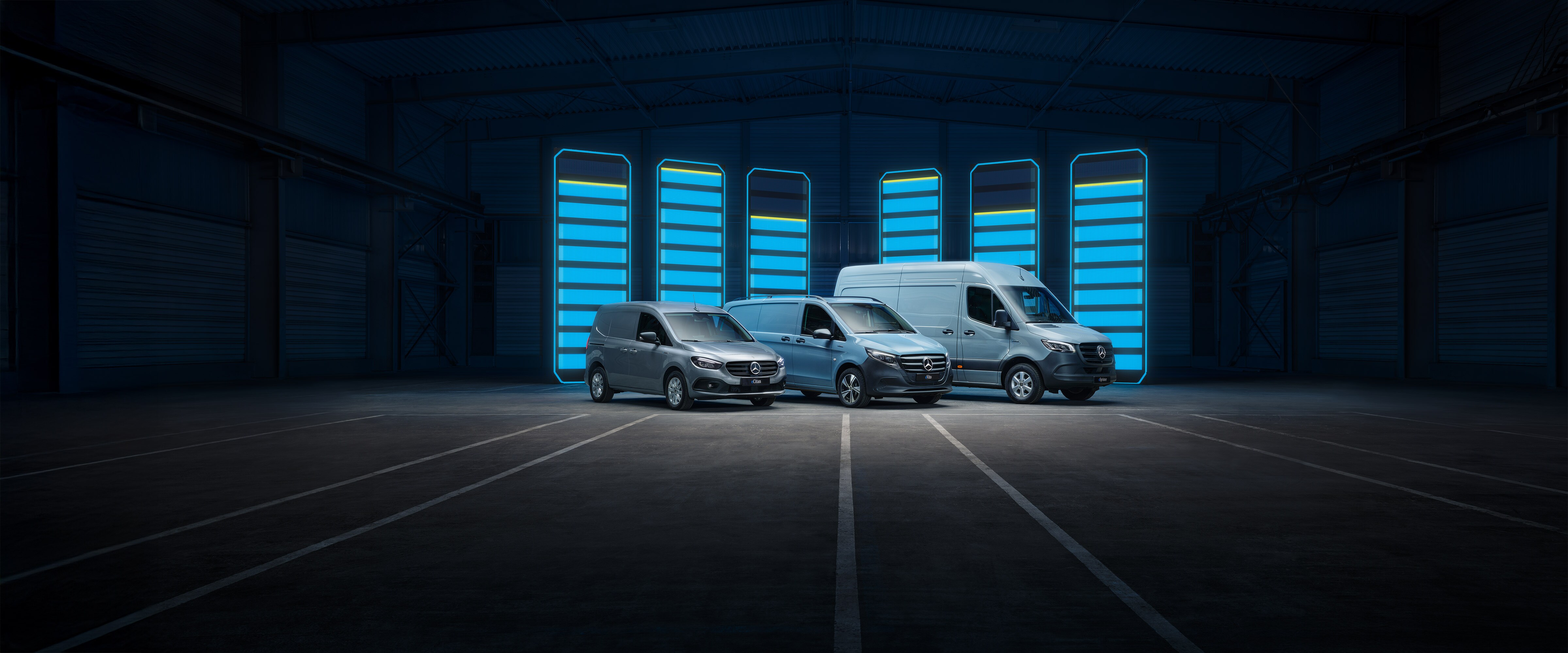 Tre veicoli commerciali Mercedes-Benz si trovano in un ambiente moderno e chiaro in cemento.