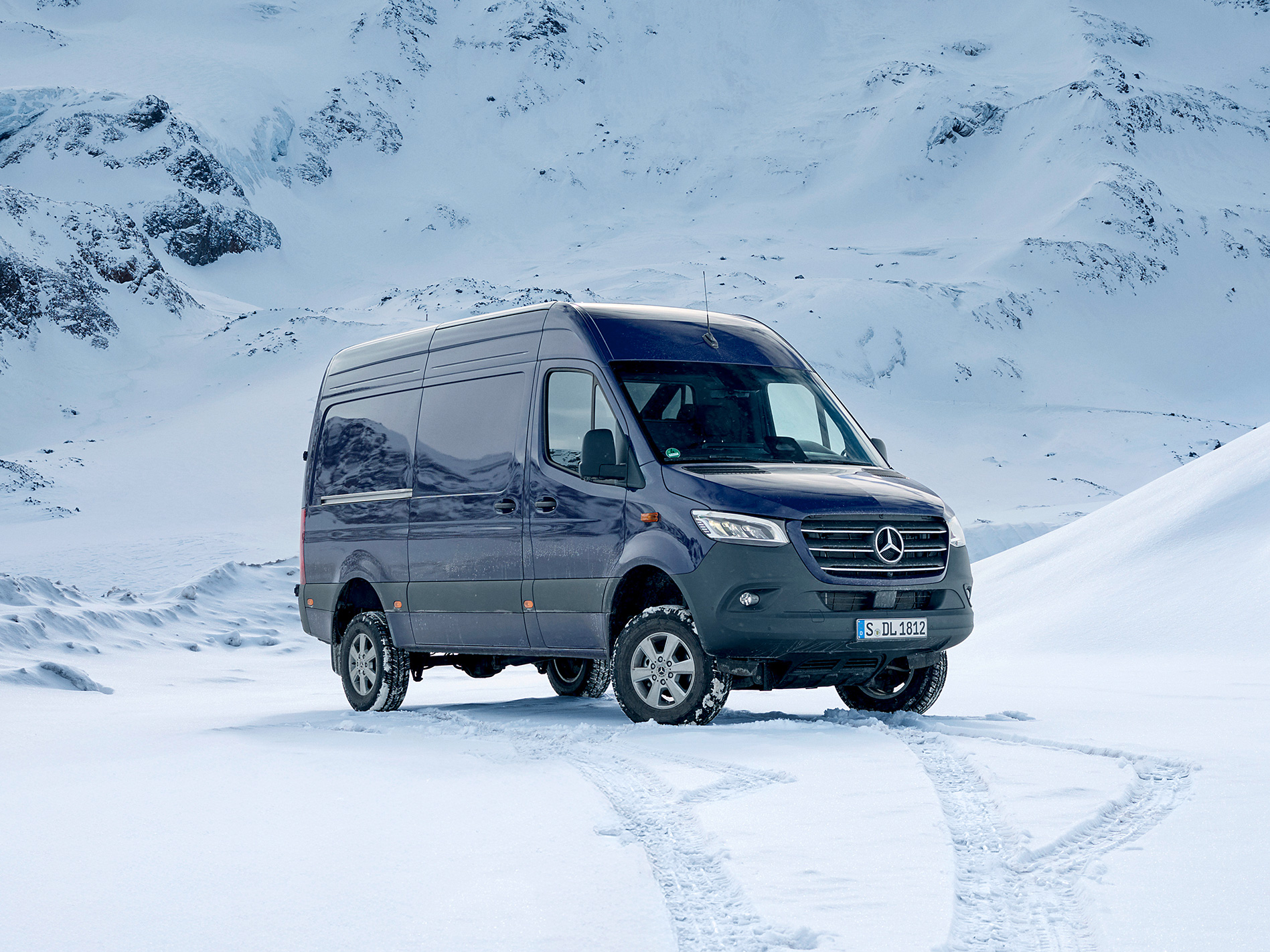 Sprinter fourgon Une Mercedes-Benz Sprinter bleu foncé est garée dans la neige devant un paysage montagneux enneigé.