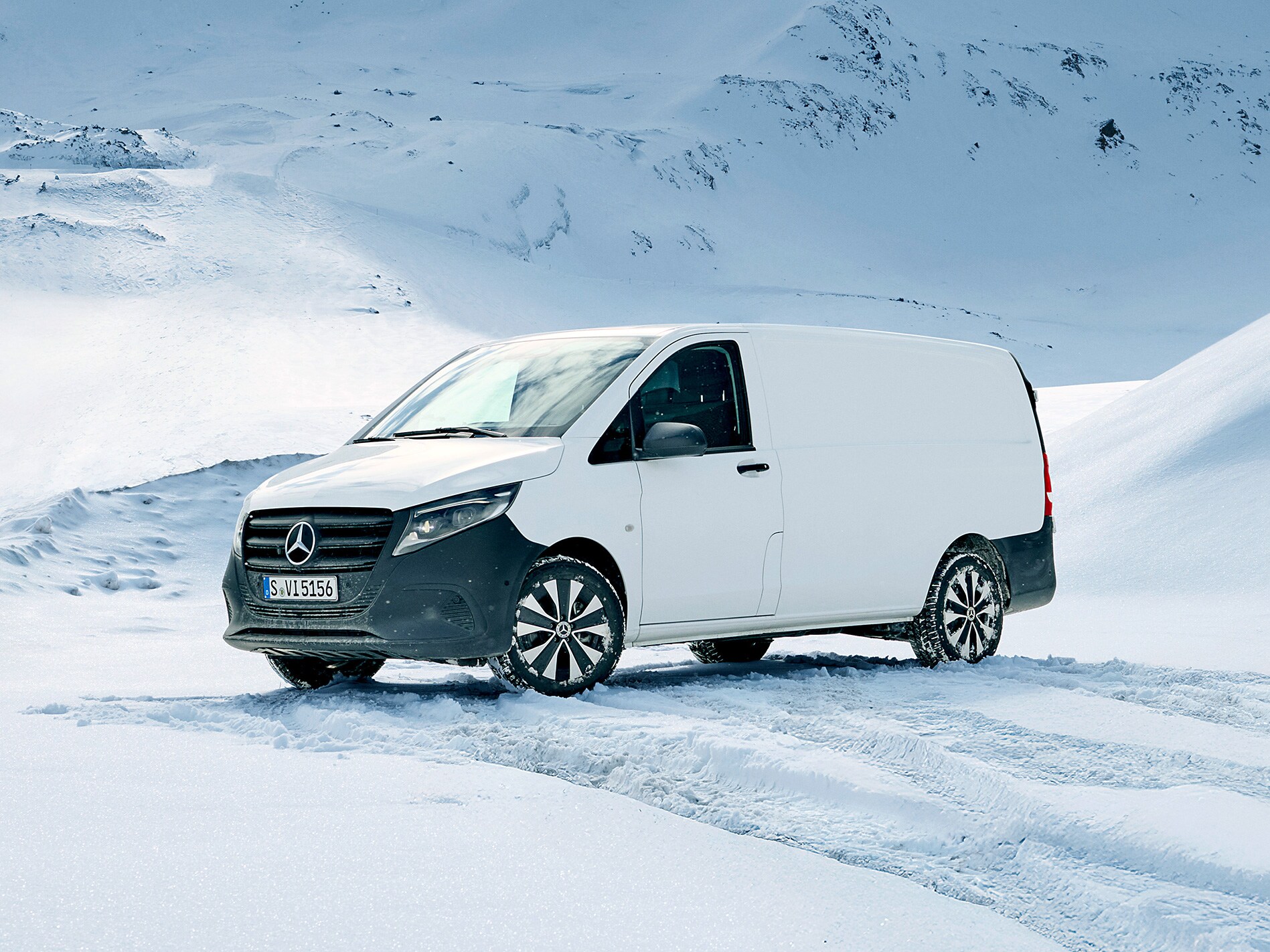 Weisser Mercedes-Benz Vito Kastenwagen im Schnee vor einer verschneiten Berglandschaft.