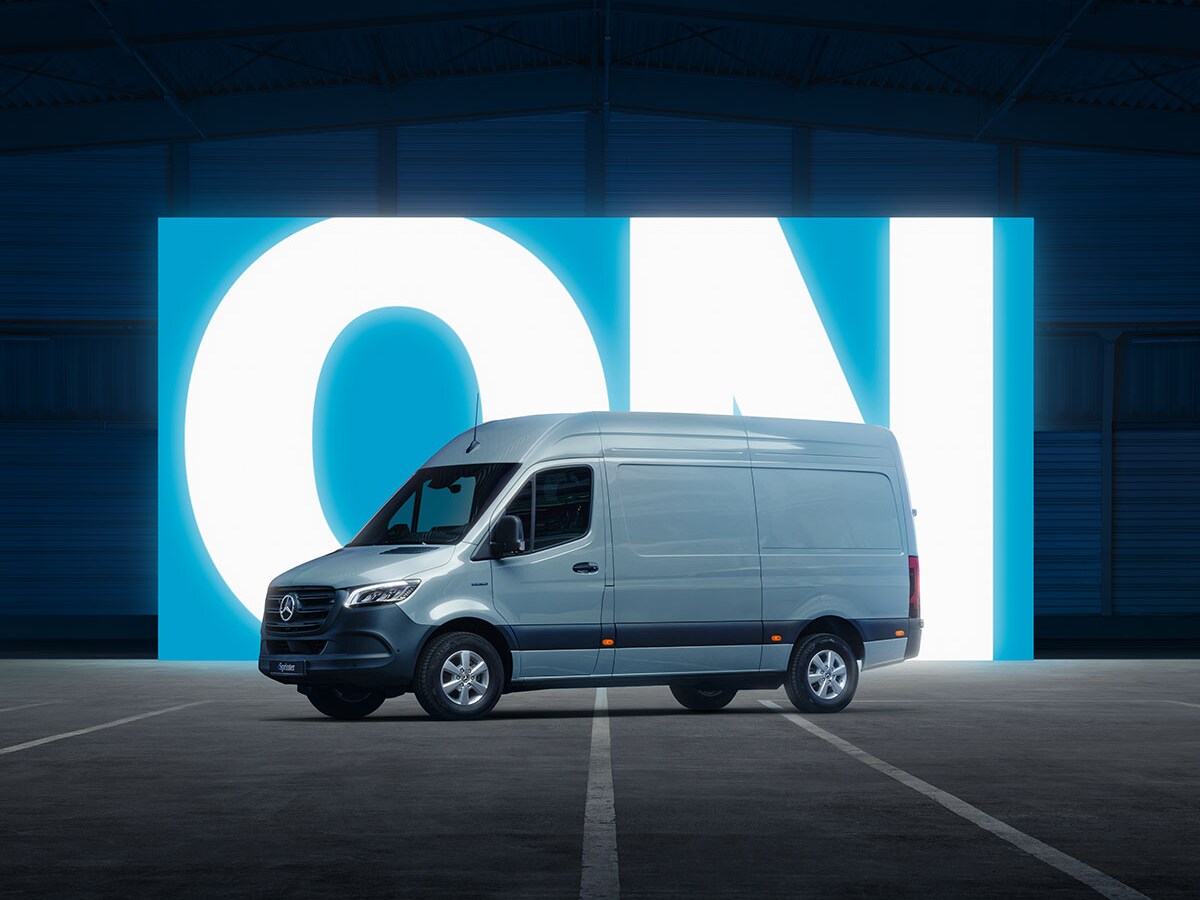 Vista laterale dell’eSprinter WORKER di Mercedes-Benz davanti alla scritta ON illuminata in un capannone buio.