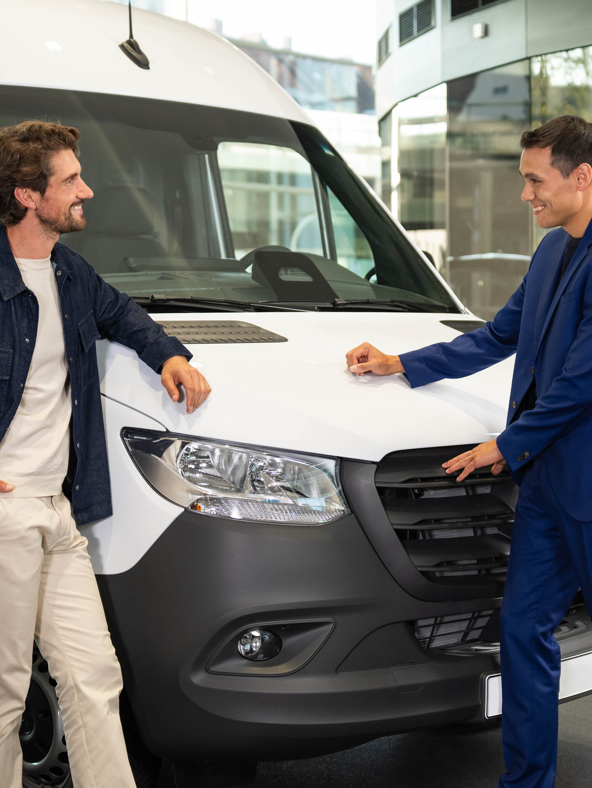 Zwei Personen lehnen sich an einen Mercedes-Benz Van und unterhalten sich.