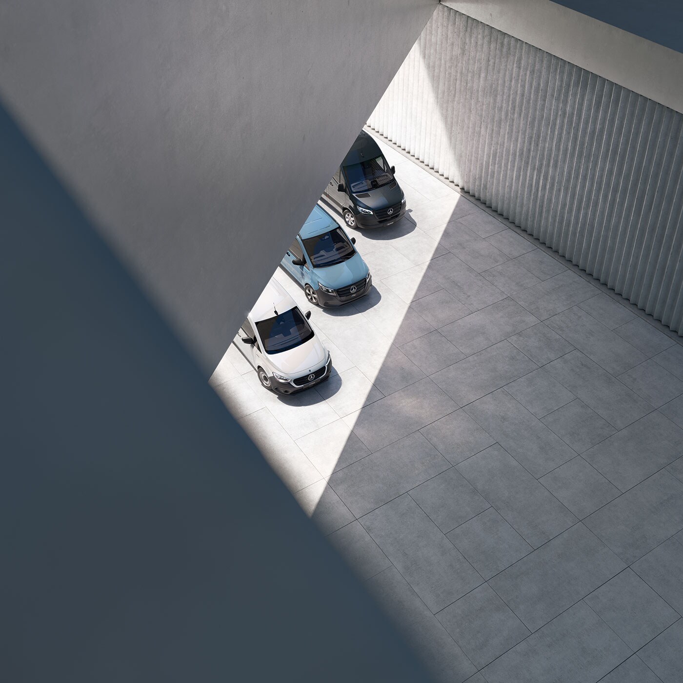 Quatre vans Mercedes-Benz garés côte à côte dans une architecture moderne avec des jeux de lumière et d’ombre.
