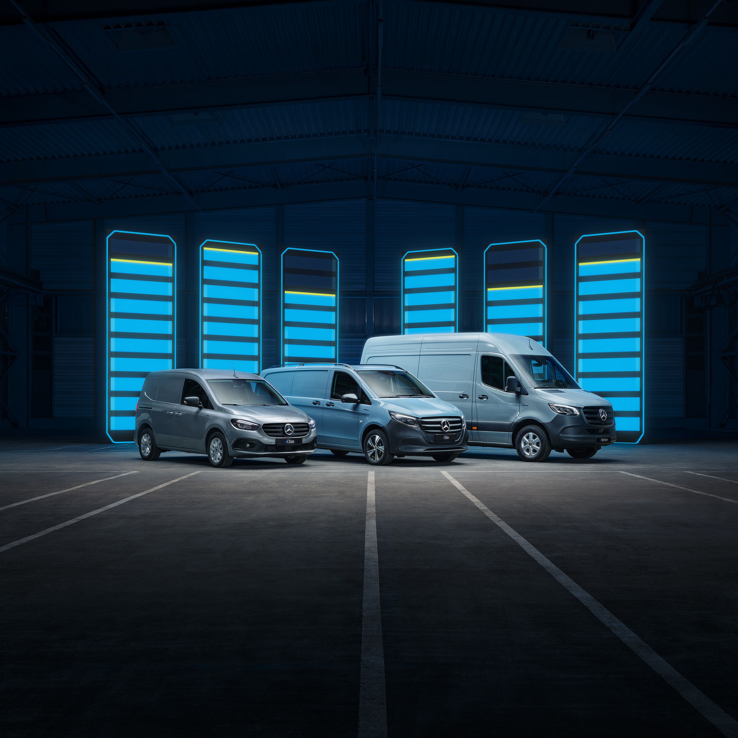 Tre veicoli commerciali Mercedes-Benz si trovano in un ambiente moderno e chiaro in cemento.