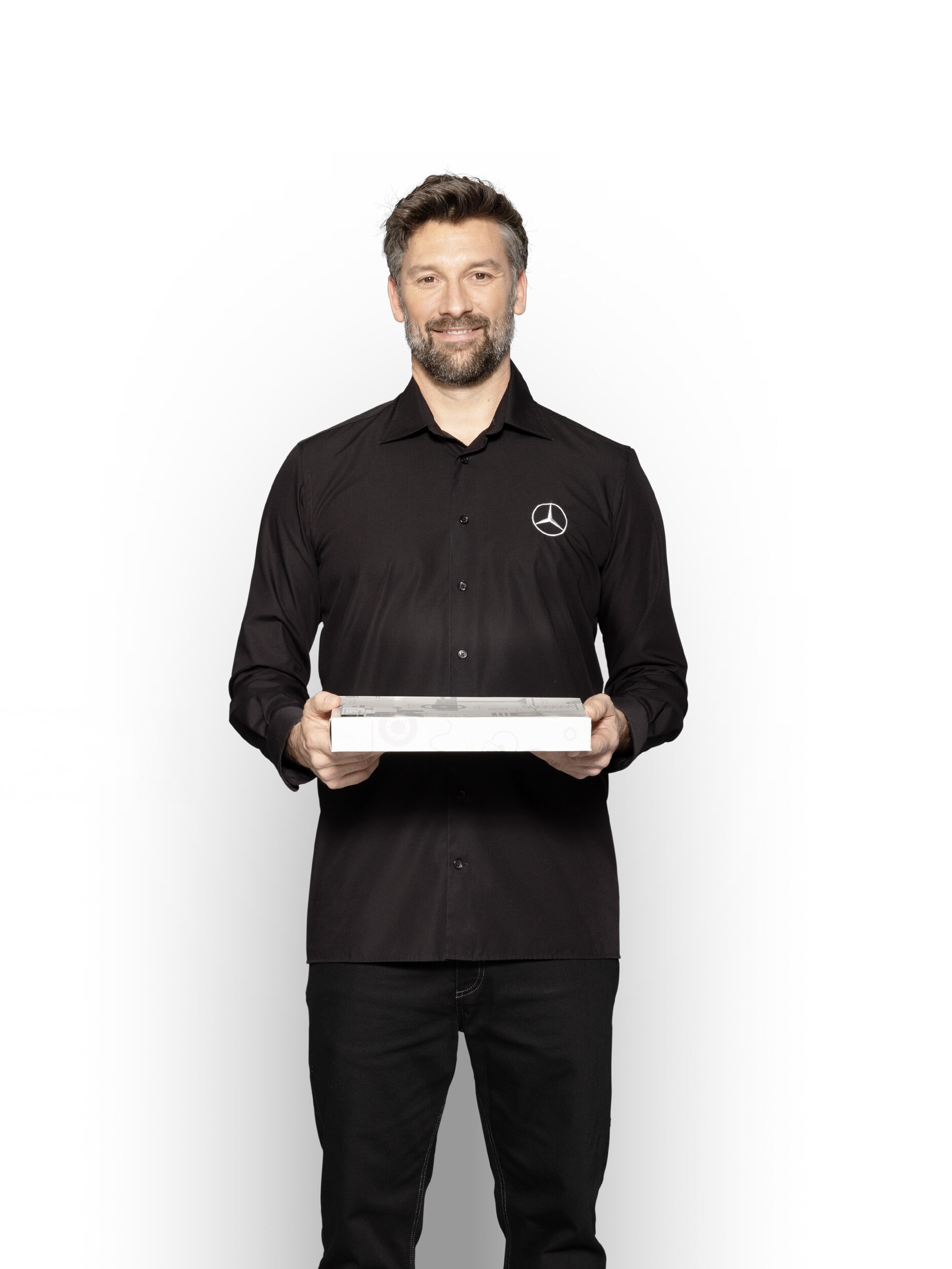 Mercedes-Benz Techniker mit einer Box in der Hand, um Mercedes-Benz Original-Teile zu zeigen.